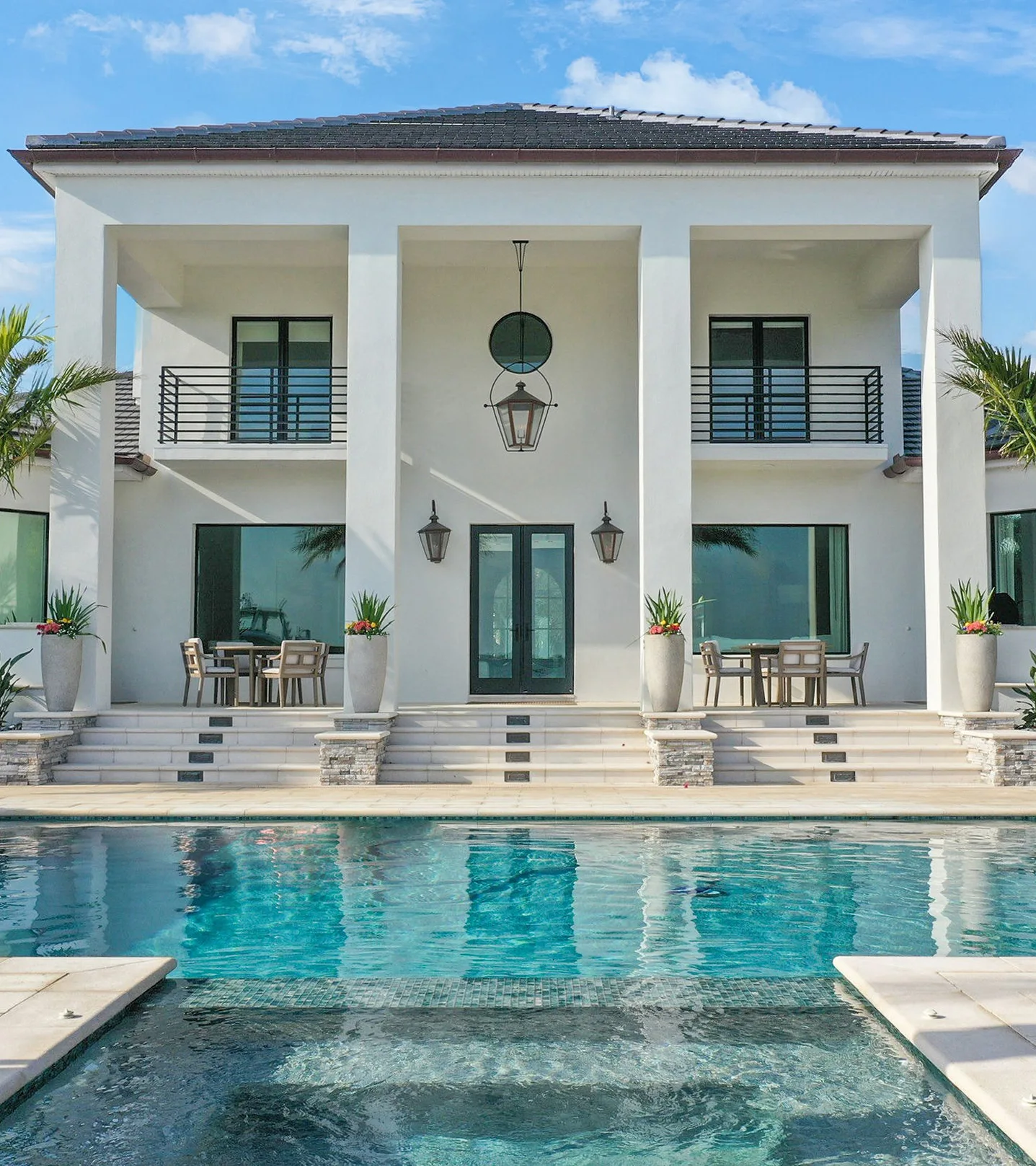 Luxury modern white residence with infinity pool, featuring contemporary architecture, black metal railings, and sophisticated outdoor living spaces in St Petersburg, FL.