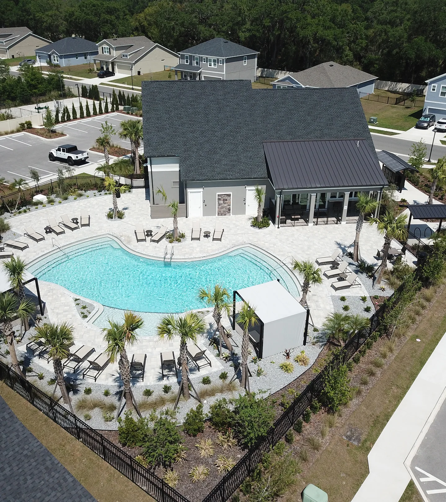 Aerial view of turquoise swimming pool with lounge chairs, white cabana, and manicured landscape design in St Petersburg residential community