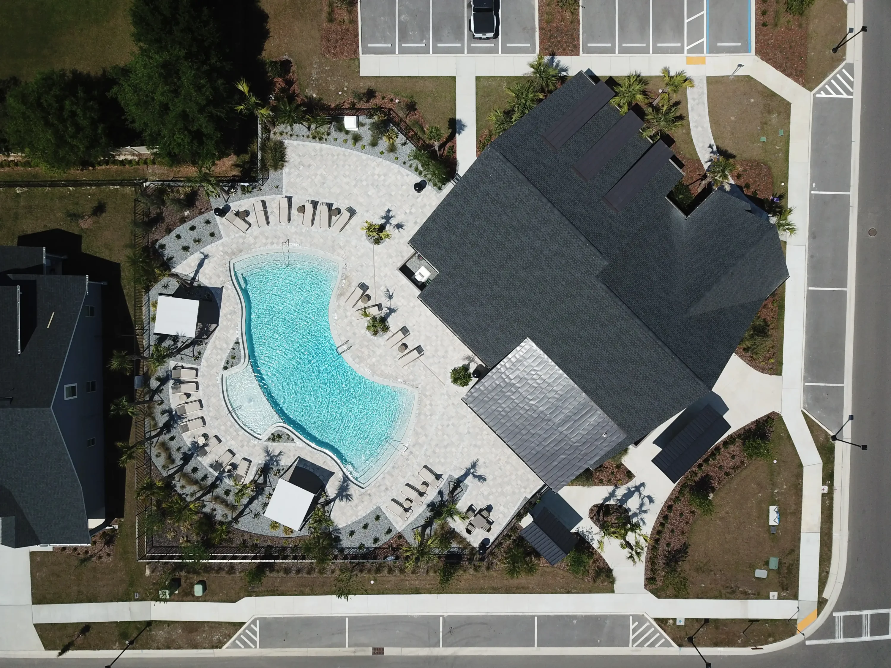 Aerial view of luxury pool with curved white deck, lounge chairs, and modern homes in St Petersburg residential community