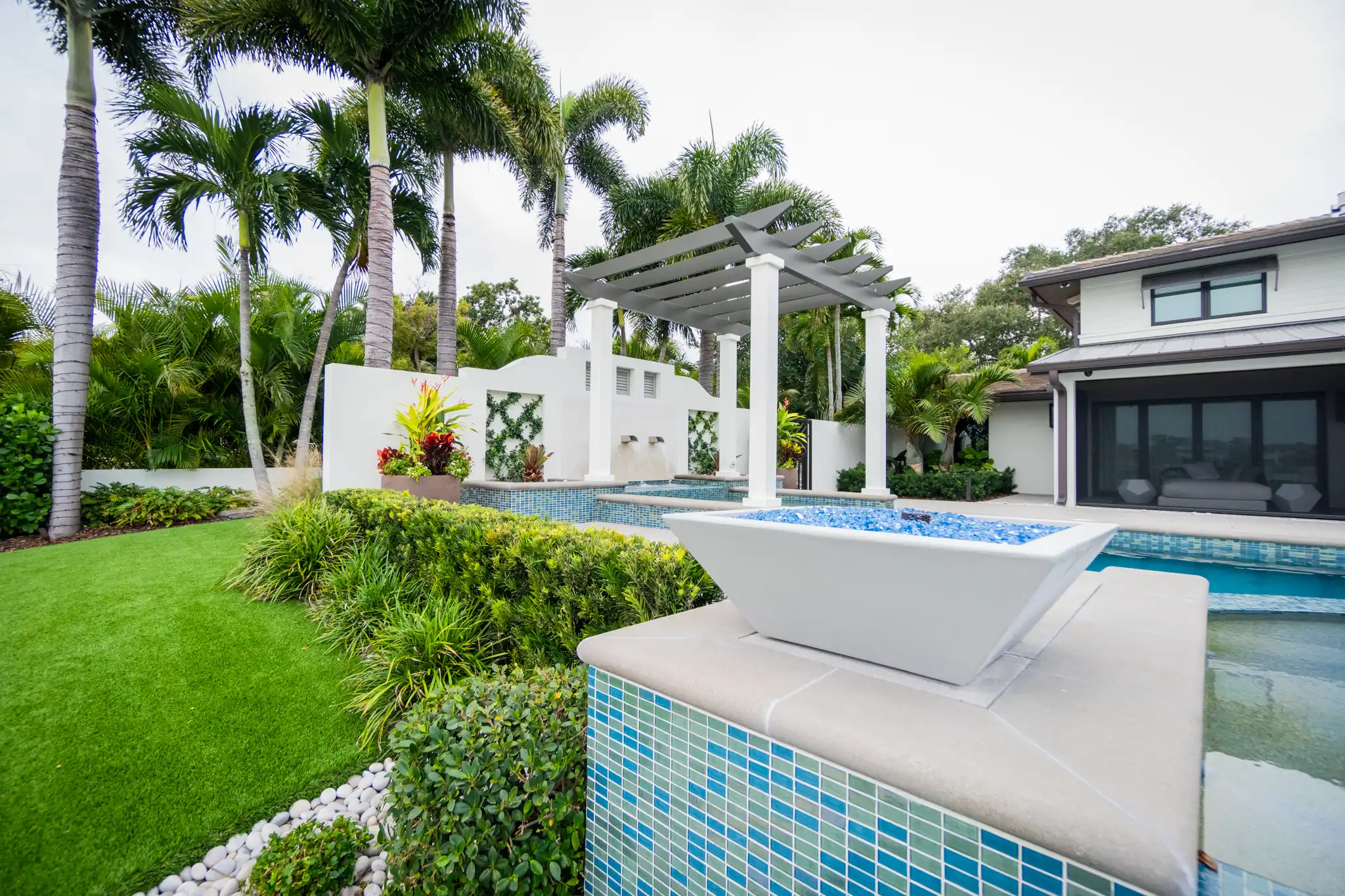 Luxury backyard with resort-style pool, spa, and modern white home featuring landscape architecture and palm trees in St Petersburg, FL.