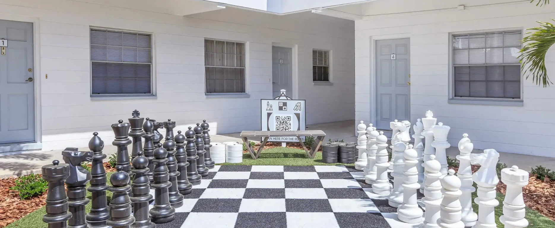 Oversized black and white chess pieces on checkered board in luxury residential courtyard with modern architecture, St Petersburg FL.