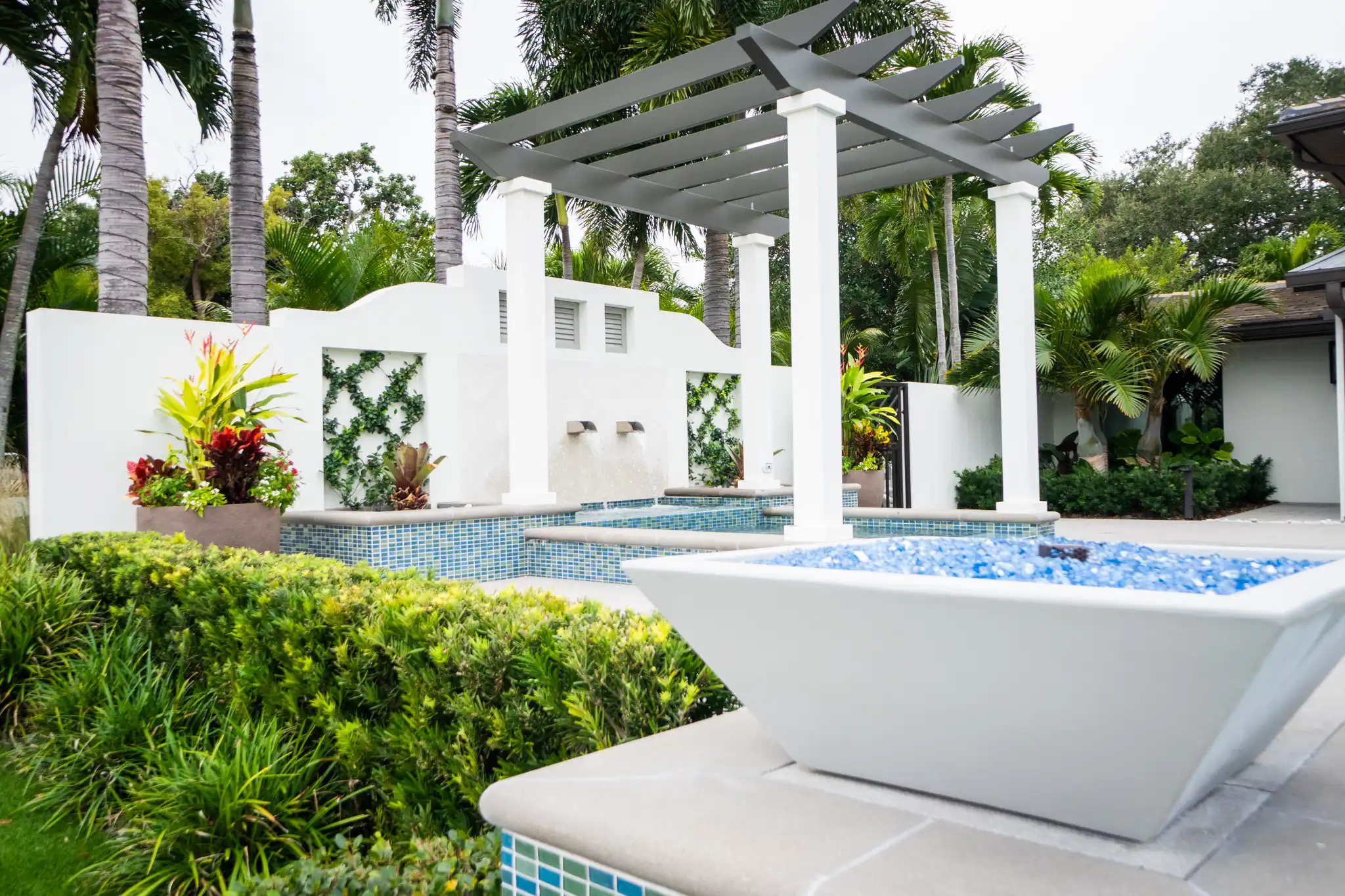 Contemporary white pergola structure overlooking luxury pool with blue mosaic tile accents, tropical landscaping, and modern architectural design in St Petersburg residential community.