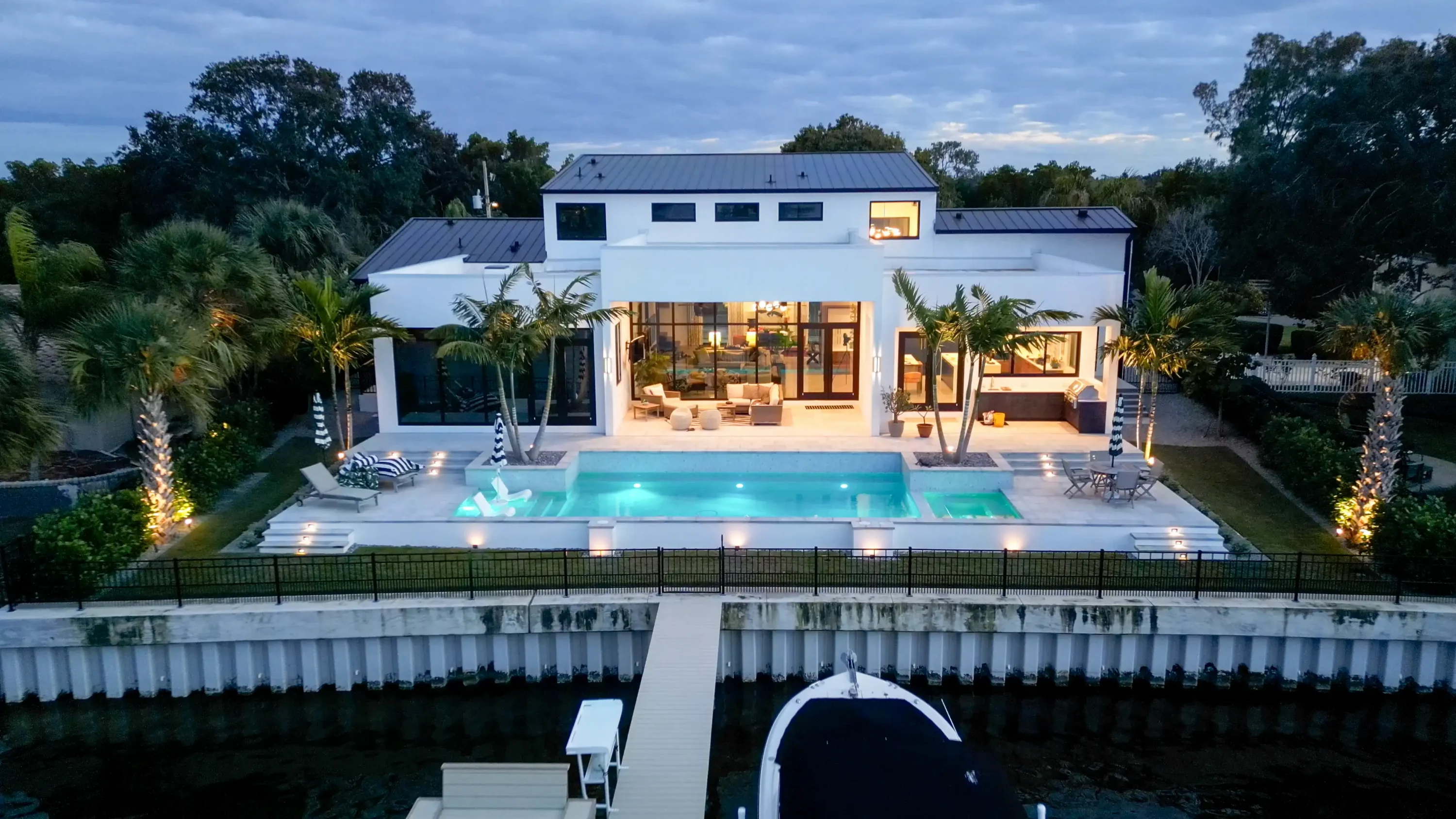 Contemporary white home with lit pool deck, palm landscaping, and waterfront access in St Petersburg, Florida luxury residential community.