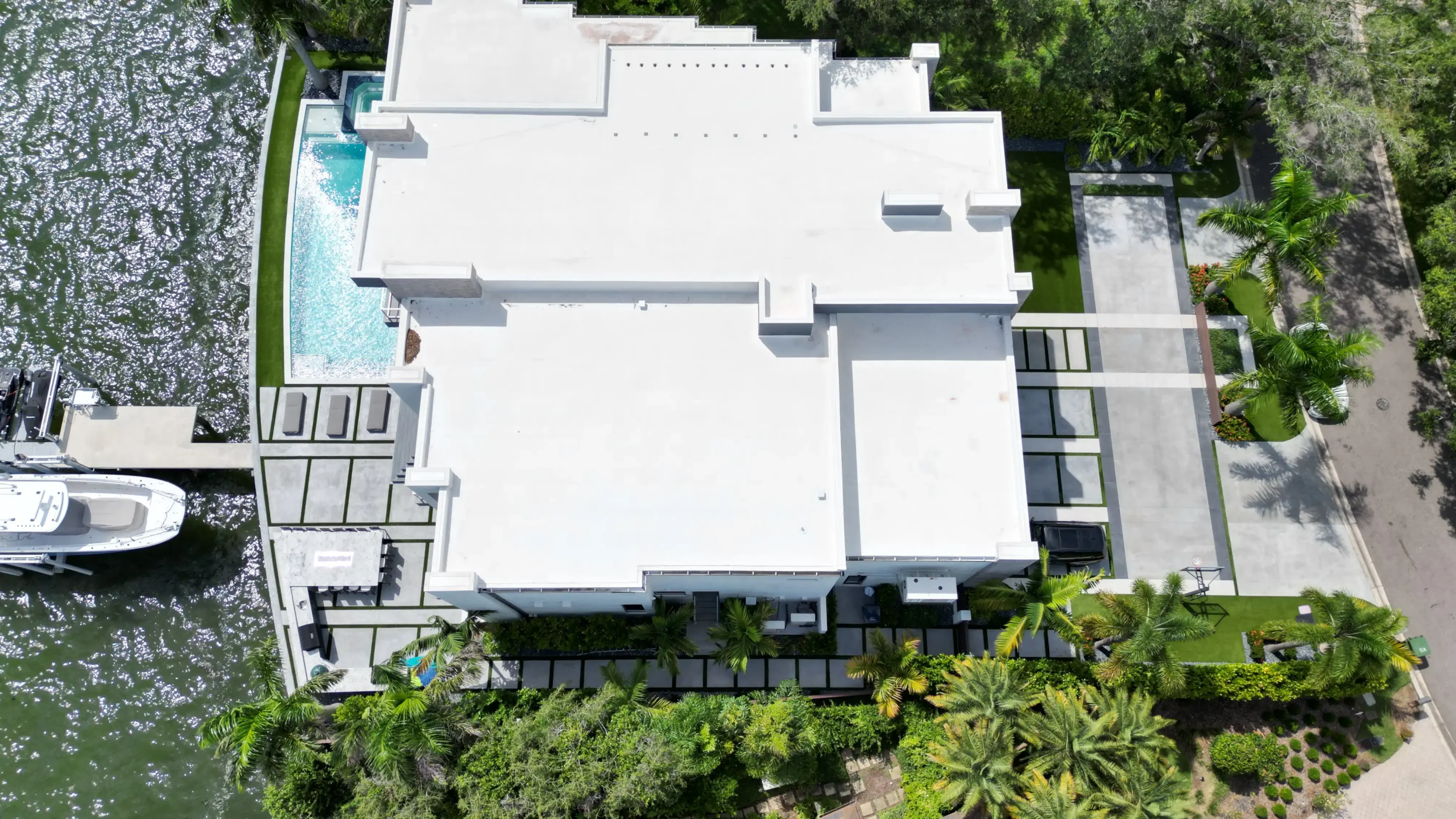 Aerial view of contemporary white home with pool, dock, and manicured landscape on St Petersburg waterfront property.
