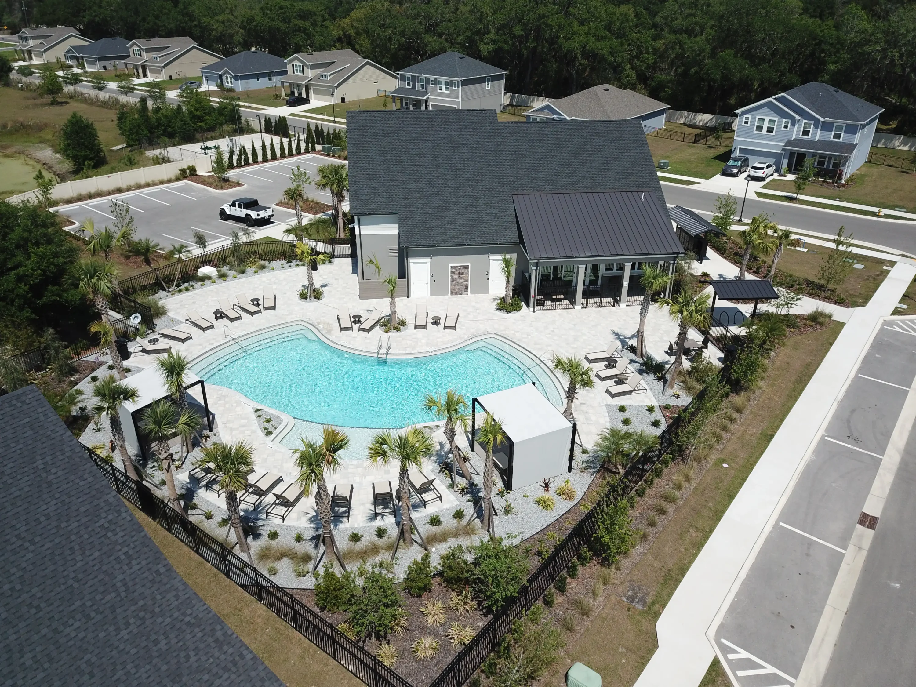 Aerial view of curved resort-style pool with cabanas, lounge chairs, and palm landscaping in St Petersburg residential community