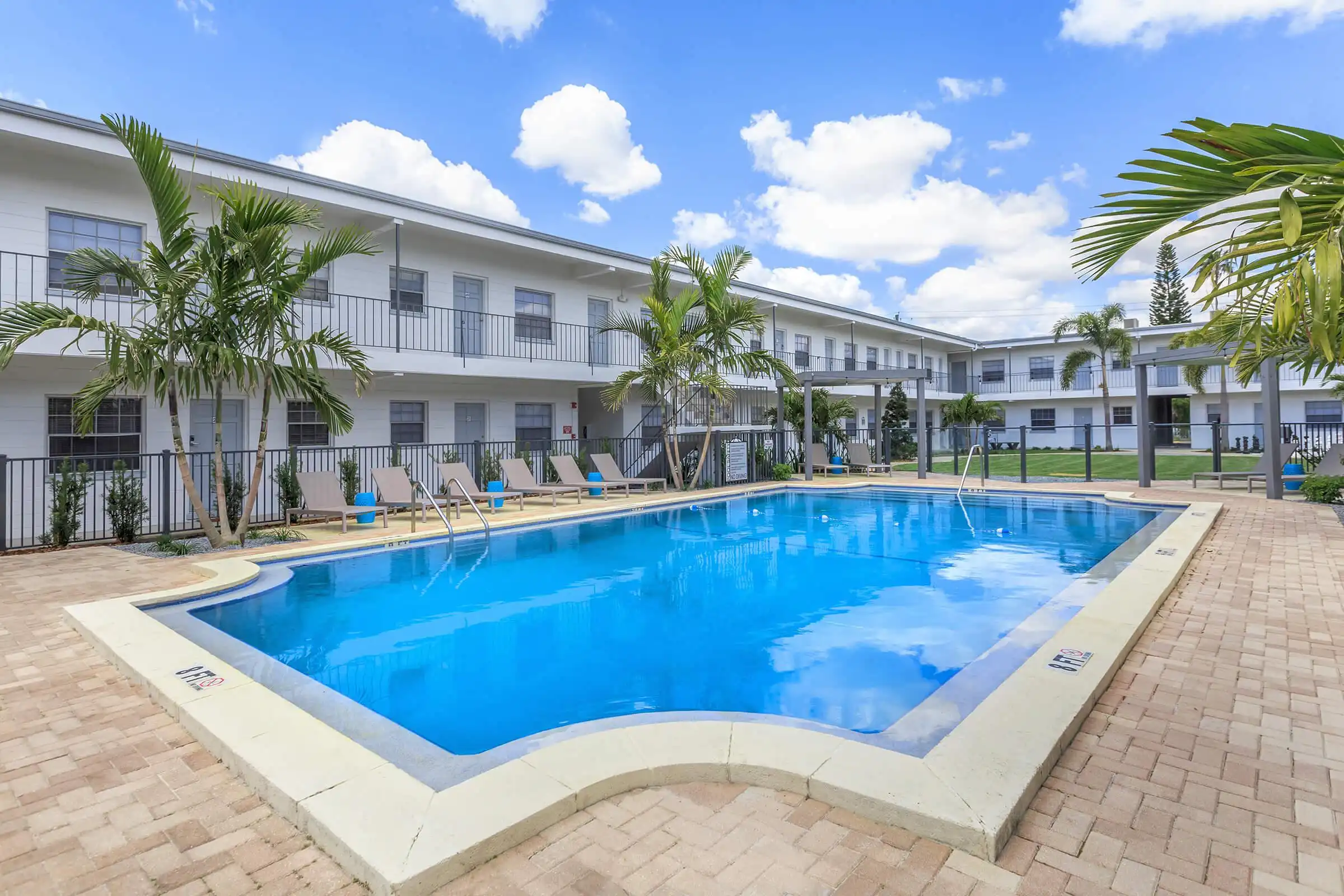 Sparkling blue resort pool with white contemporary buildings, palm trees, and lounge chairs in St Petersburg luxury residential community