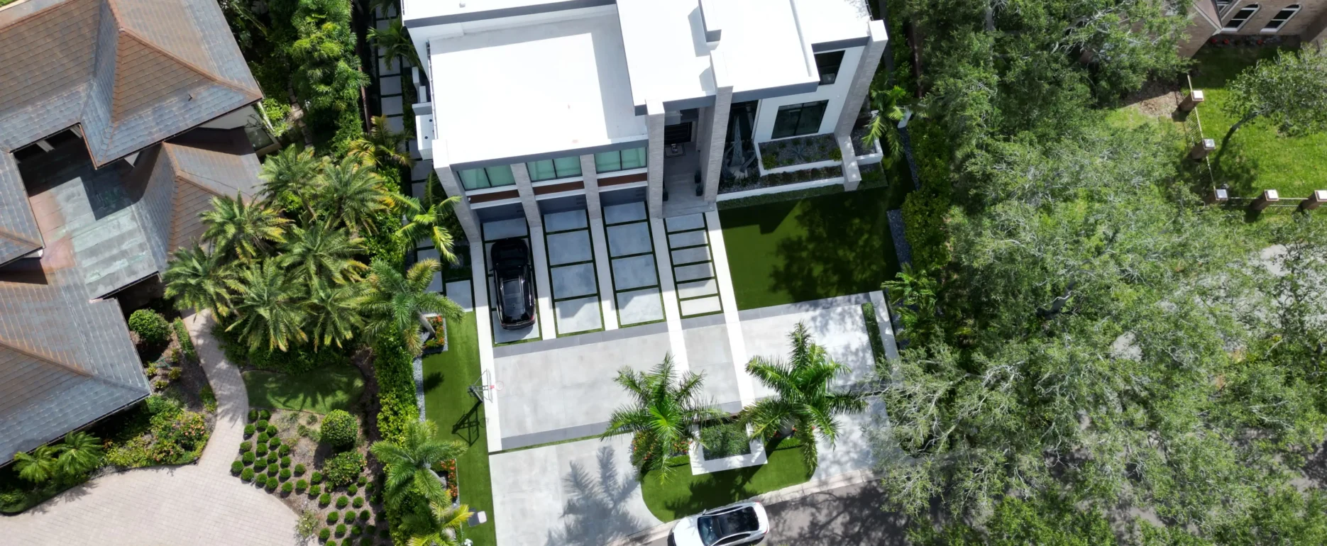 Aerial view of contemporary luxury home with white roof, large windows, manicured lawn, and mature landscaping in St Petersburg residential community.