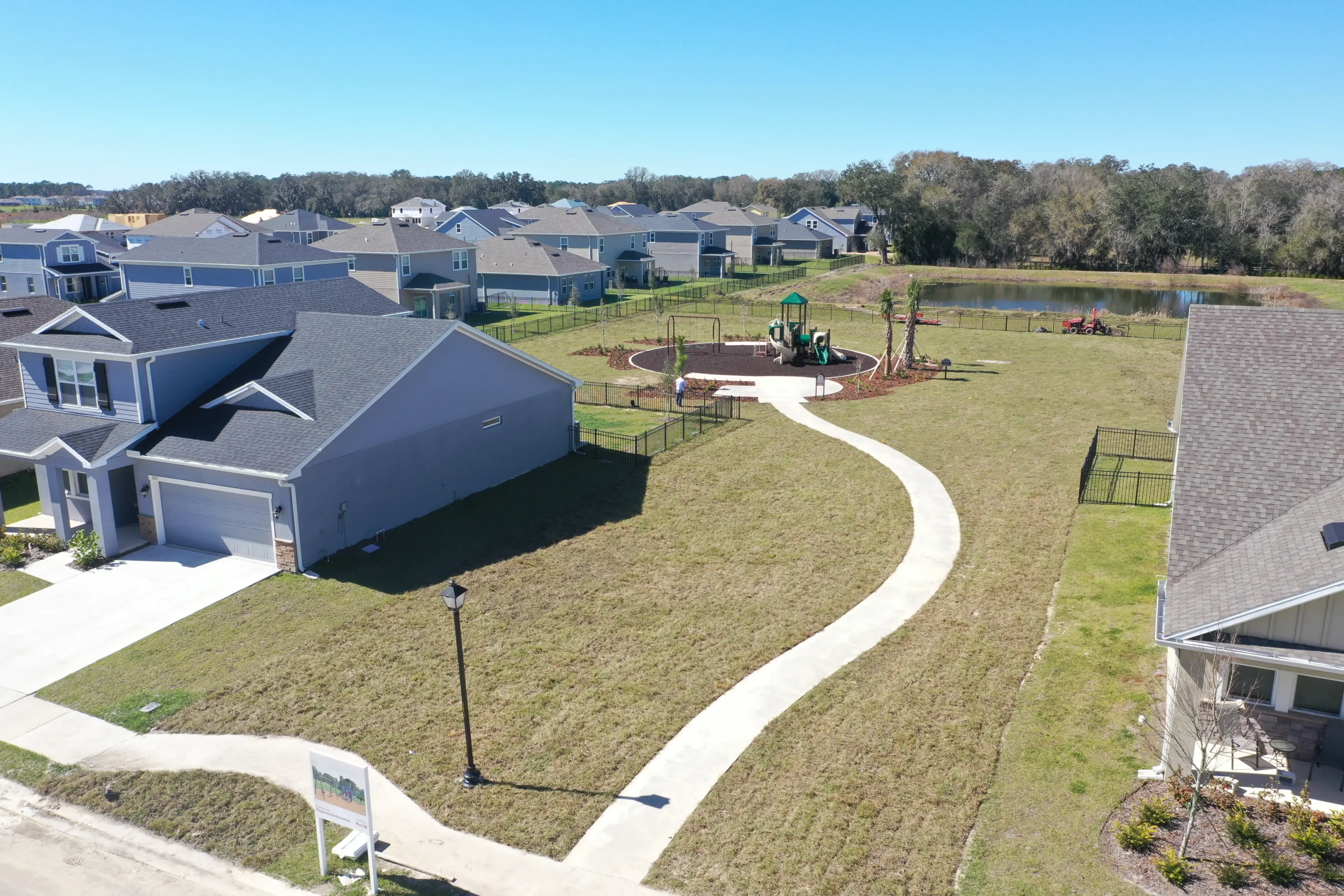 Aerial view of residential community with playground, curved sidewalk, and homes overlooking waterfront in St Petersburg, FL luxury development.