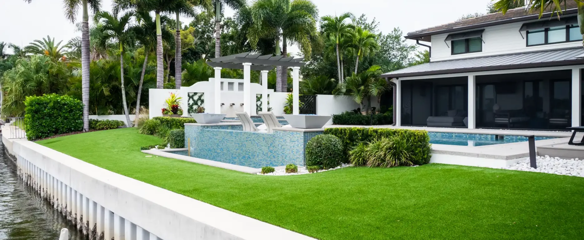 Luxury waterfront home with infinity pool, manicured lawn, and palm trees in St Petersburg residential community