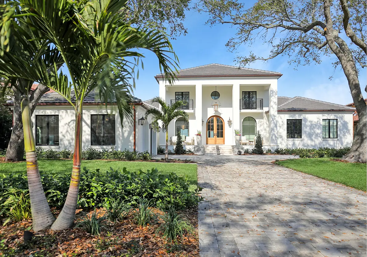 Elegant white stucco colonial residence with arched entryway, black-trimmed windows, and manicured landscape in St Petersburg, FL