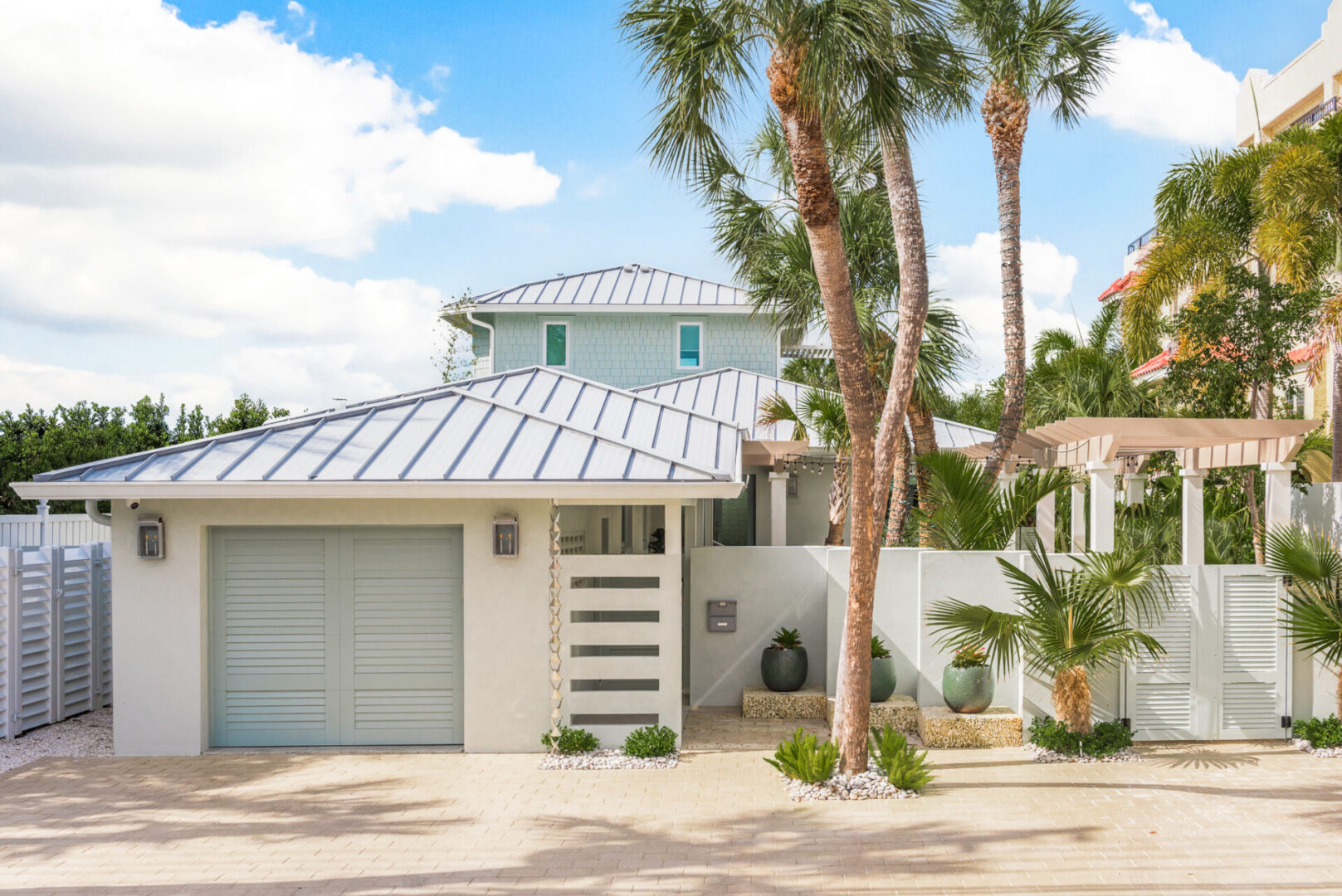 Modern white residential home with standing seam metal roof and palm trees in St Petersburg, FL showcasing luxury outdoor design and landscape architecture.