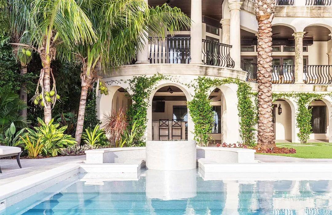 Luxury residential courtyard with circular pool, white colonial architecture, ivy-covered arches, and manicured landscape in St Petersburg.