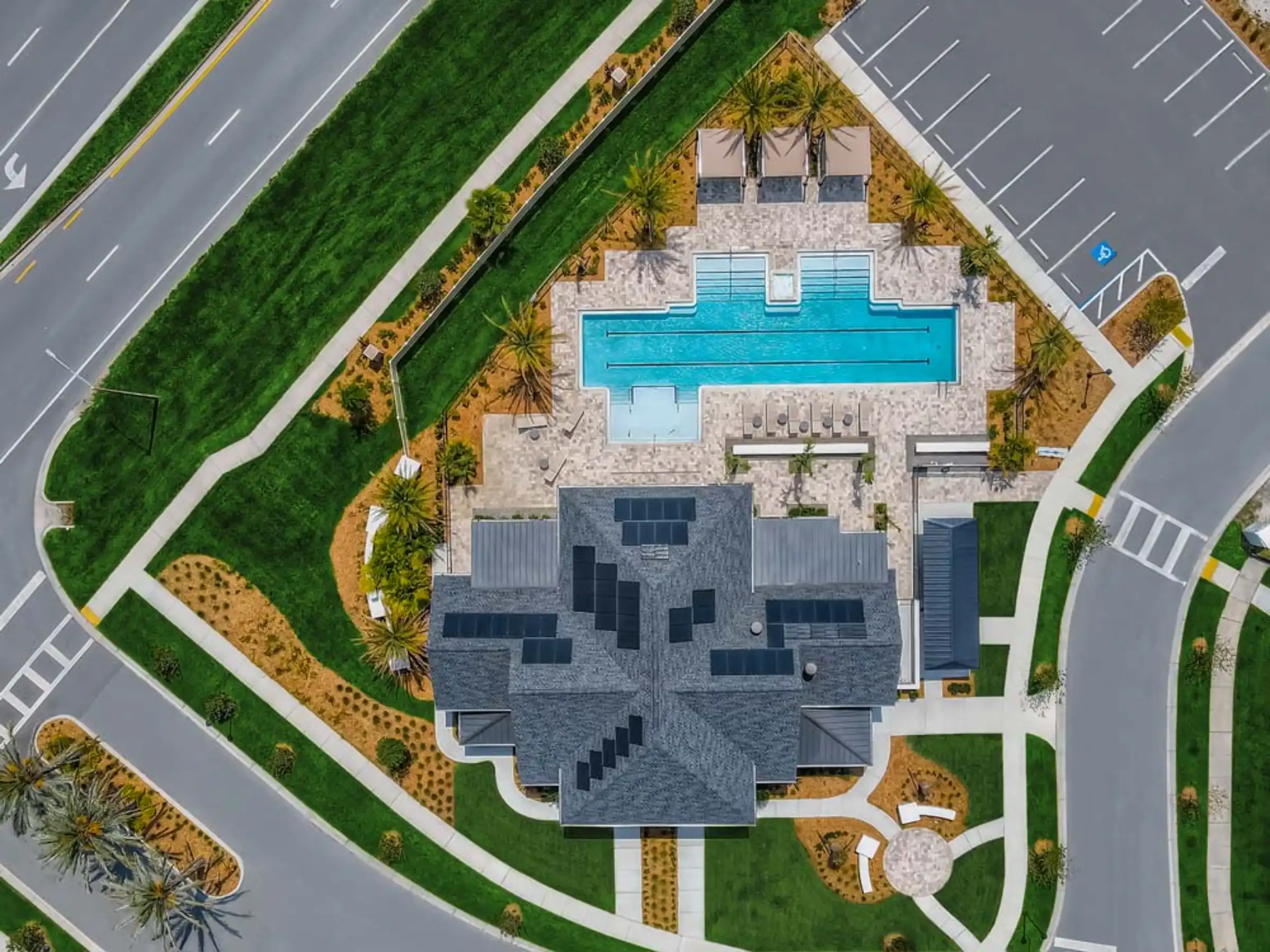 Aerial view of contemporary residential home with distinctive gray stone facade and bright turquoise lap pool surrounded by manicured lawns and palm trees in St Petersburg, FL.