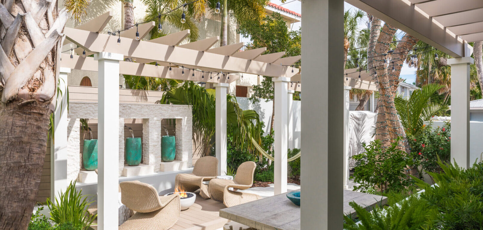 Modern pergola with beige lounge chairs and fire pit overlooking lush tropical landscaping in Saint Petersburg luxury residential design.