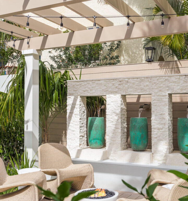 Modern courtyard with cream pergola, woven lounge chairs, and turquoise planters against white stone architecture in St Petersburg luxury residential design.