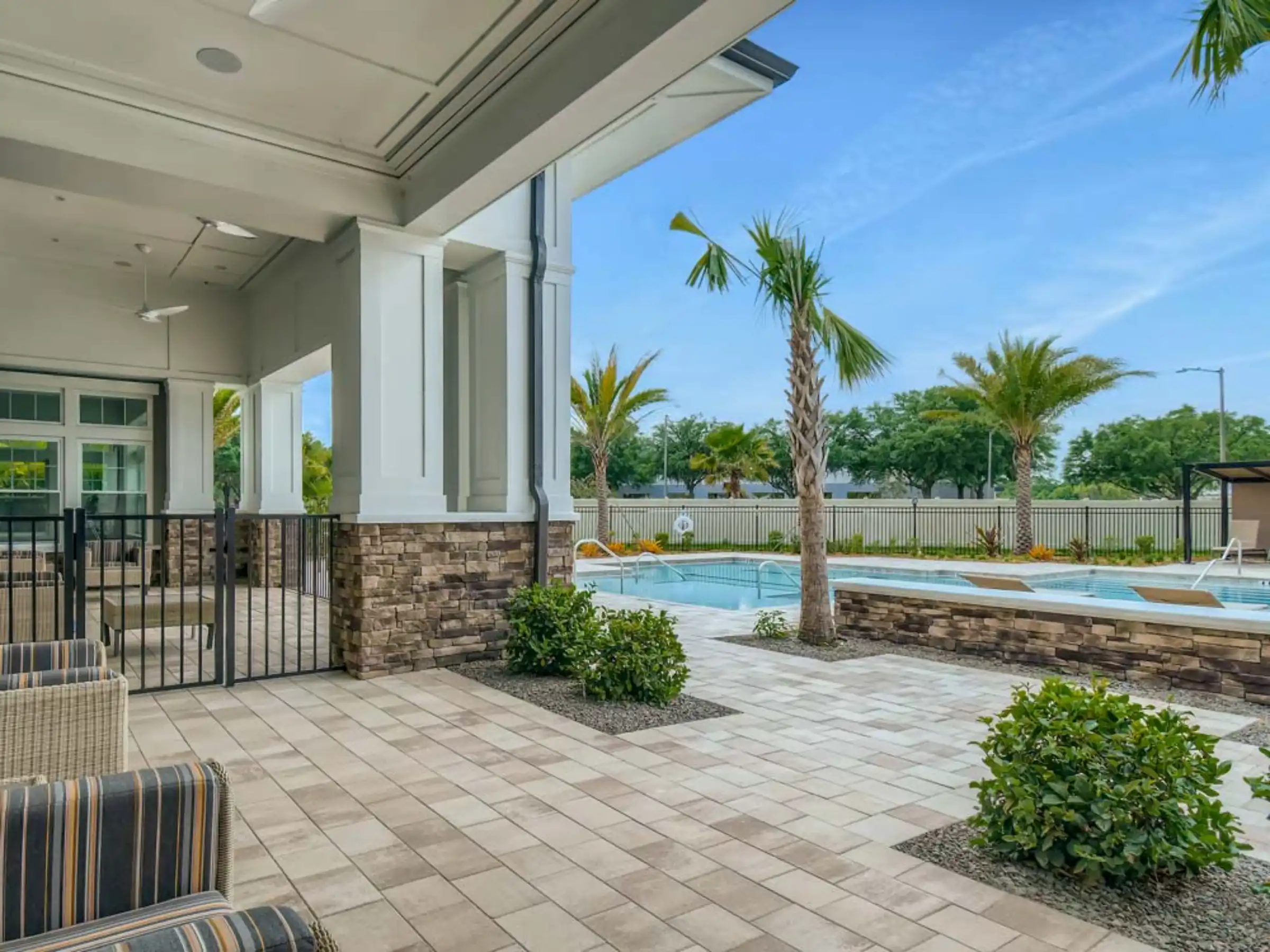 Luxury pool area with covered pavilion, stone columns, and palm trees overlooking residential community in St Petersburg, Florida.