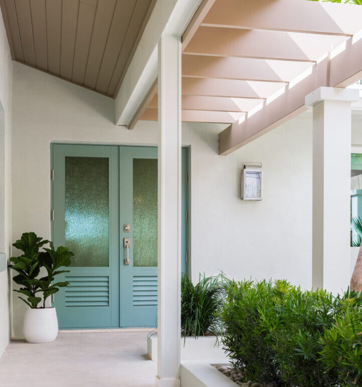Modern St Petersburg luxury home entrance with turquoise textured door, white columns, pink beam ceiling, and landscape design with manicured greenery.