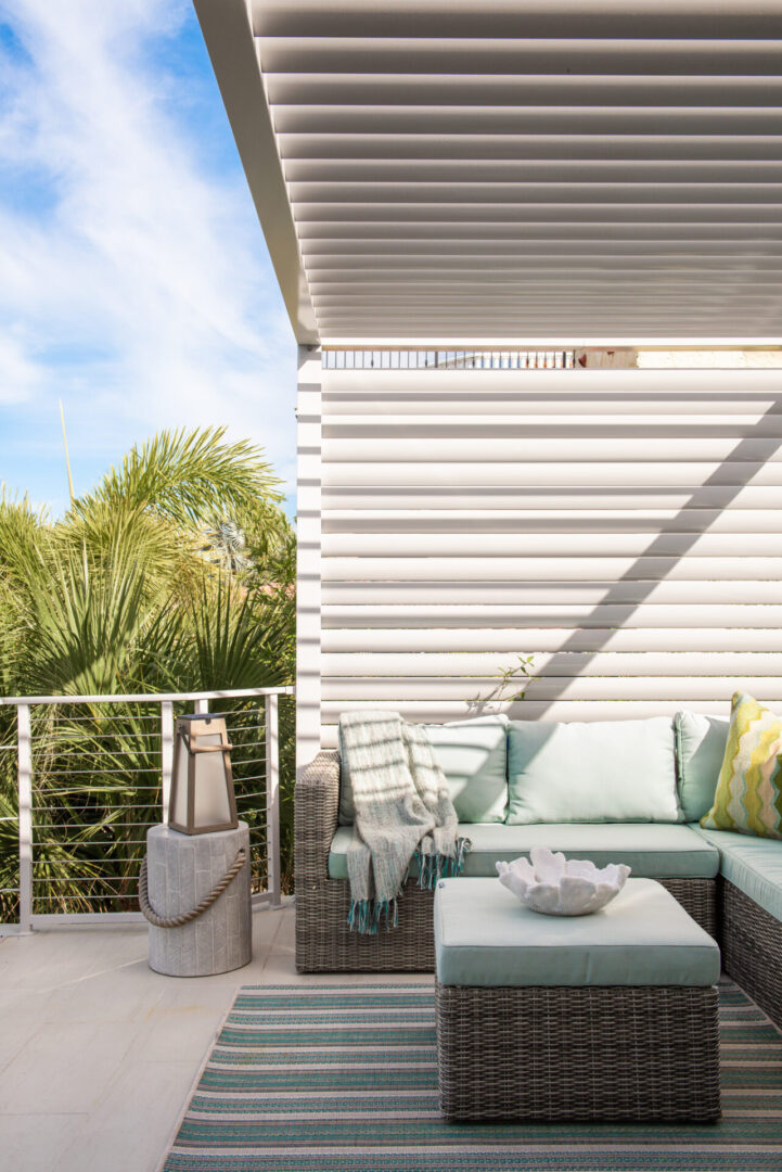 Luxury outdoor lounge with gray wicker sectional, mint cushions, and motorized pergola shade structure overlooking tropical landscaping in St Petersburg.