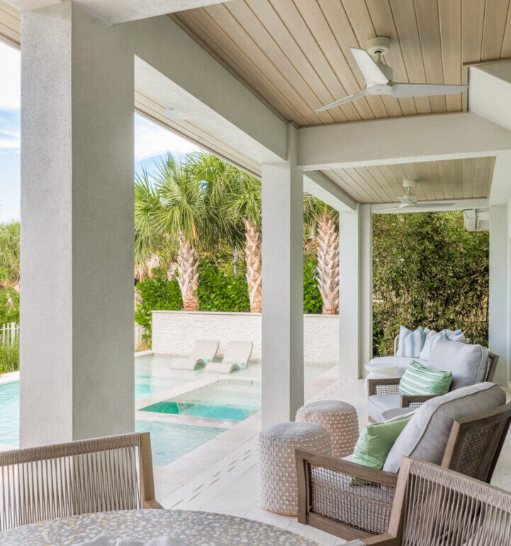 Luxury covered patio with woven lounge chairs overlooking a resort-style pool and tropical landscape in St Petersburg, Florida.