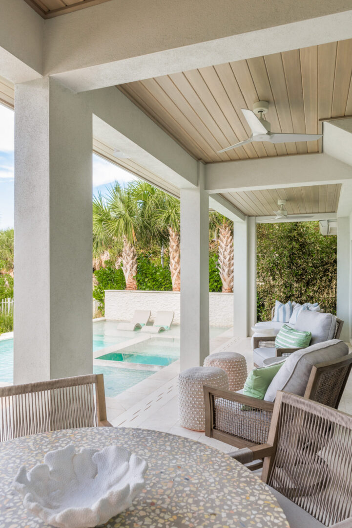 Luxury covered patio with woven lounge chairs overlooking a resort-style pool and tropical landscape in St Petersburg, Florida.