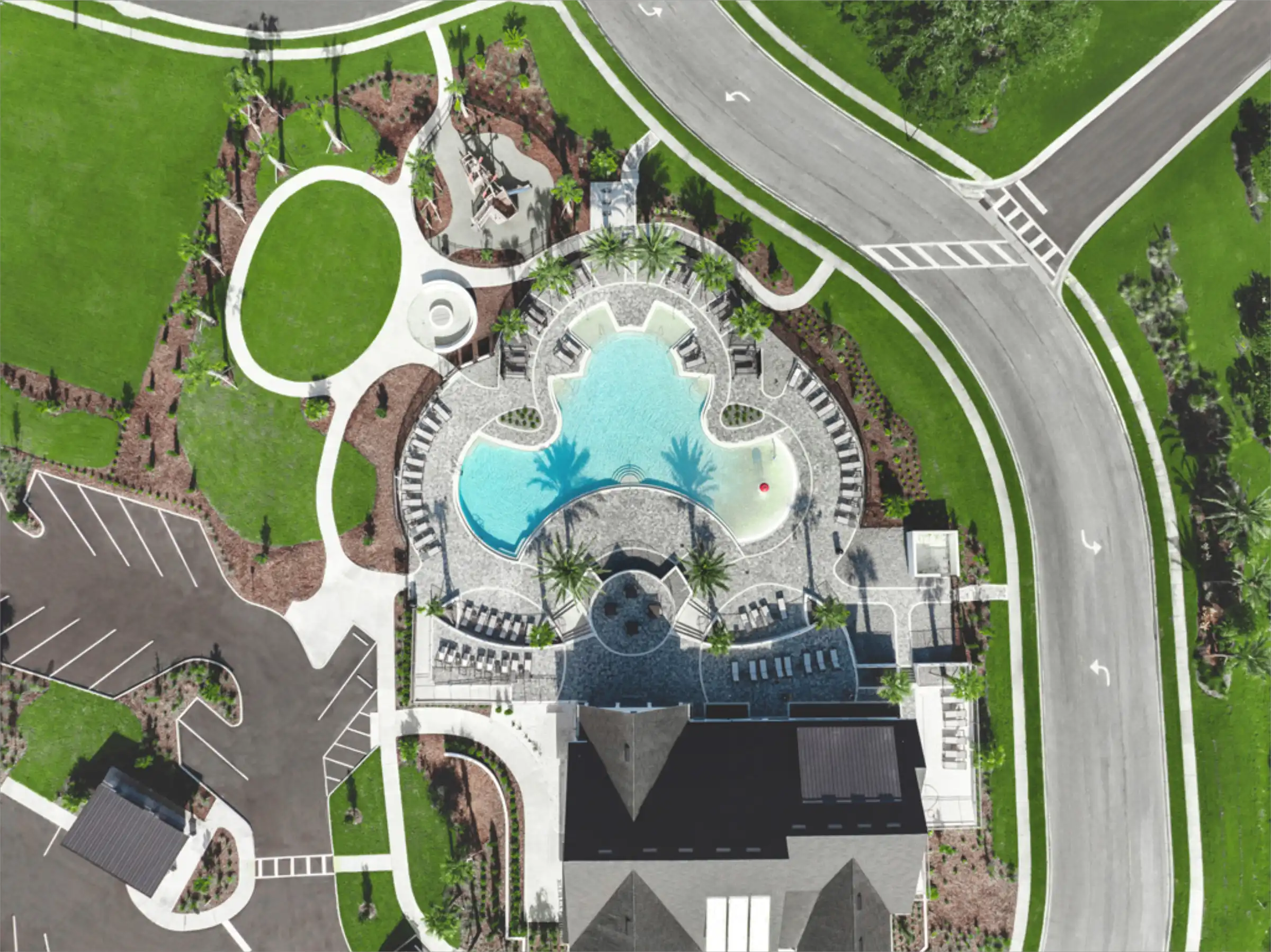 Aerial view of upscale resort with turquoise pool, curved white pathways, manicured lawns, and surrounding roads in St Petersburg, FL.