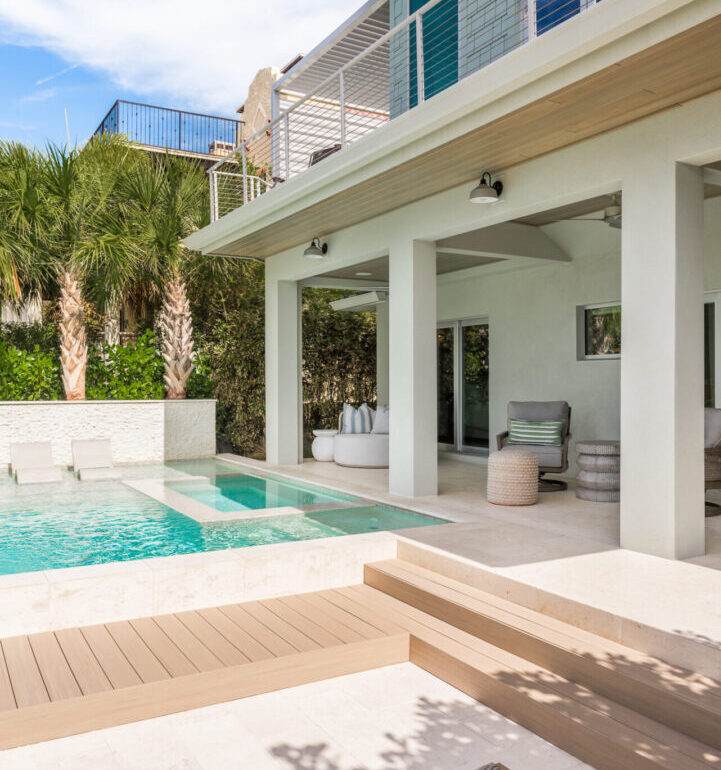 Contemporary white residential home with turquoise pool, wooden deck, and covered patio overlooking landscaped grounds in St Petersburg, FL.