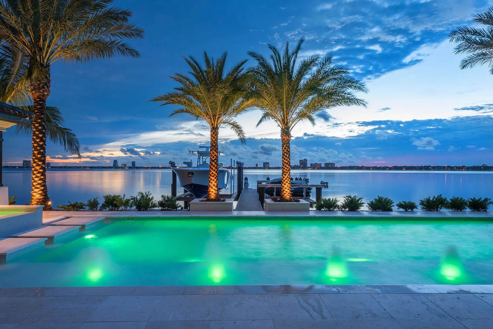 Luxury poolside with green LED lighting, palm trees, and bay views at dusk in St Petersburg, Florida.