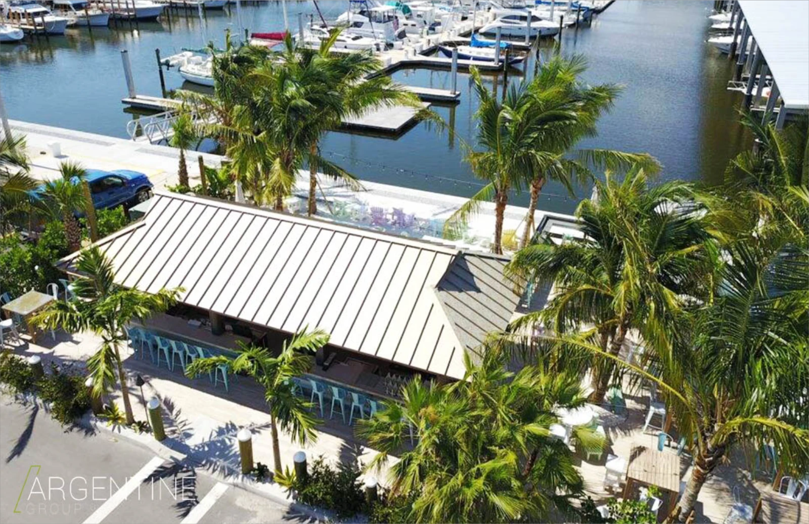 Modern pavilion with metal roof overlooking St Petersburg marina, surrounded by palm trees and boat docks, showcasing luxury outdoor design.