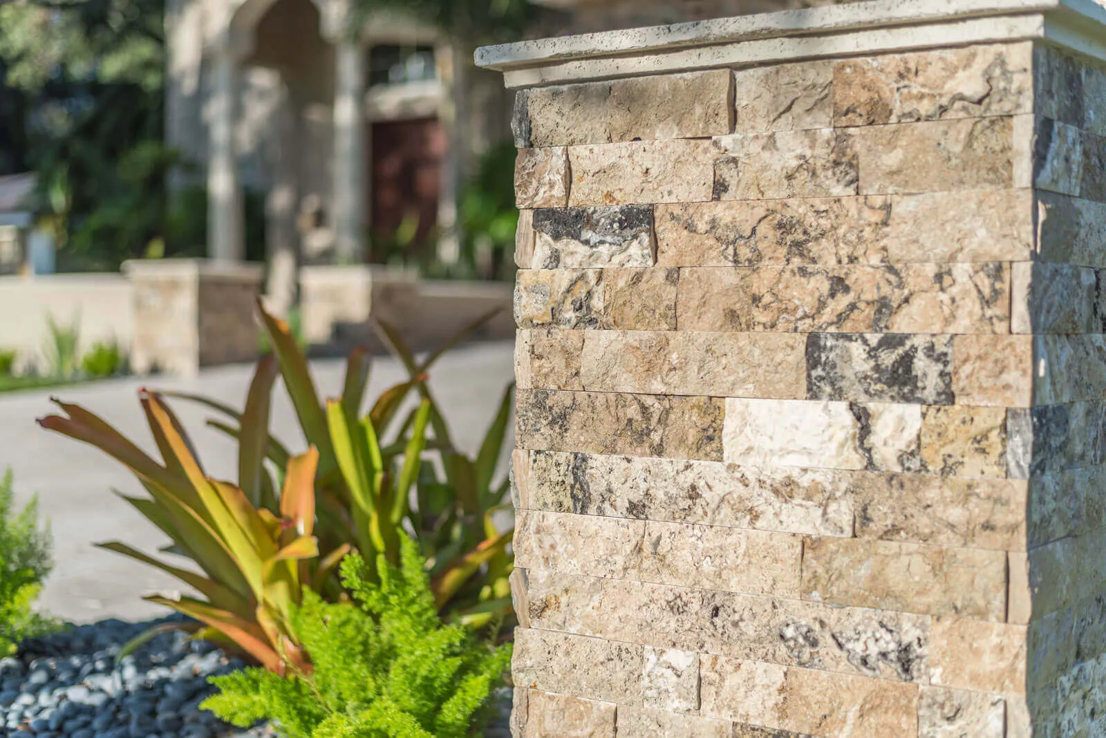 Luxury stacked stone column with tropical plants in refined St Petersburg residential landscape design.