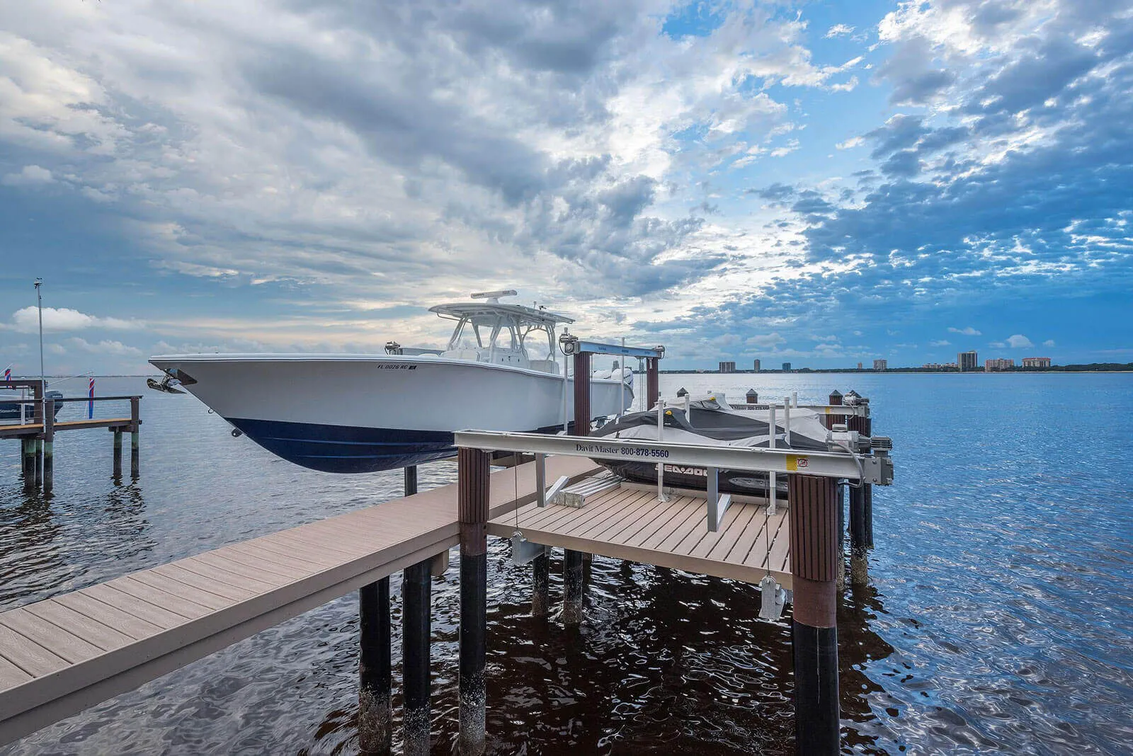 White and navy sportfisher boat moored at wooden dock on calm blue water in St Petersburg, Florida with cloudy sky and distant skyline.