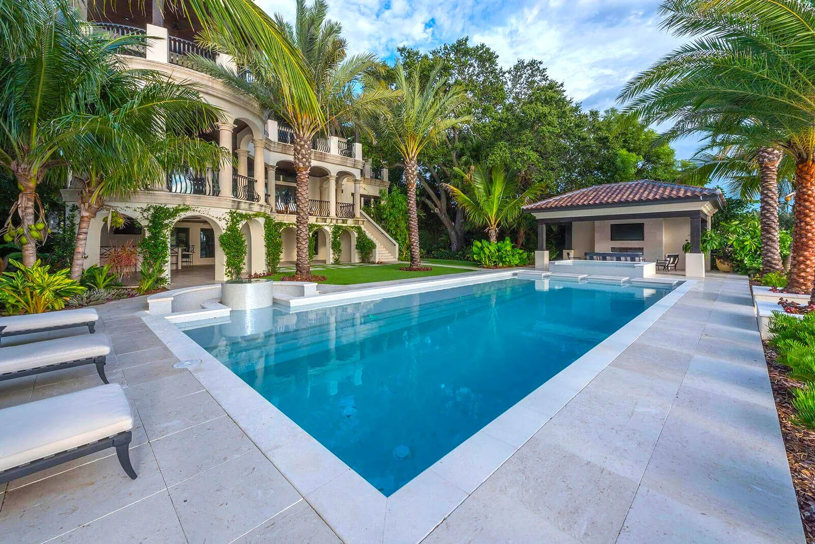 Luxury residential pool with classical columned mansion, manicured landscape design, and palm trees in St Petersburg FL