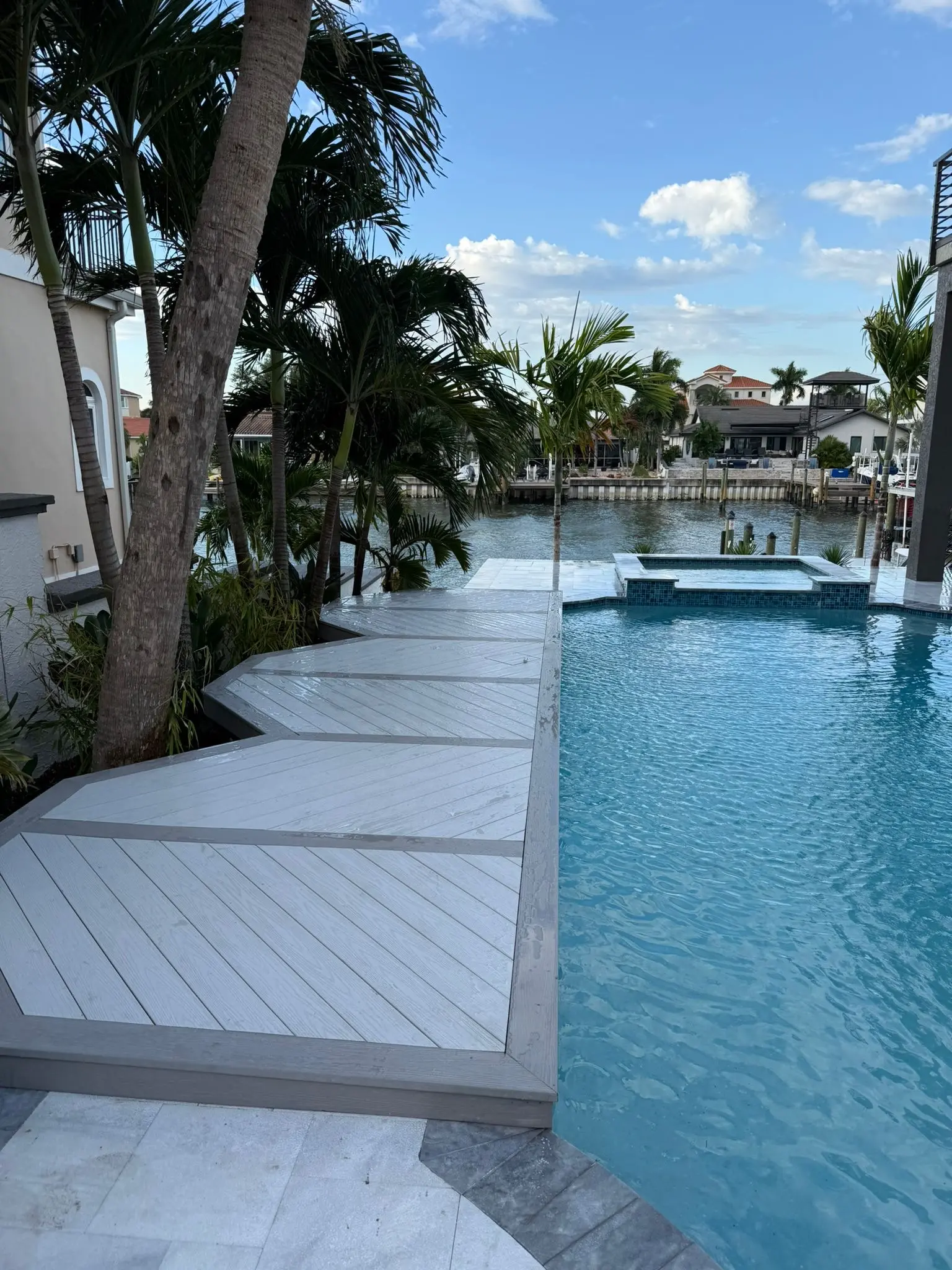 Luxury waterfront pool deck with gray composite decking, turquoise pool water, and canal views in St Petersburg, FL residential community.