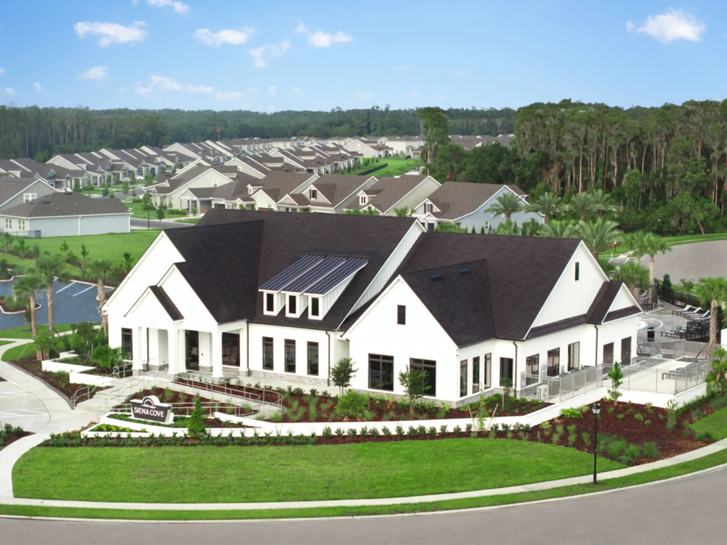 Contemporary white home with dark roof in luxury residential community featuring manicured lawn, landscape architecture, and pool design in St Petersburg FL.