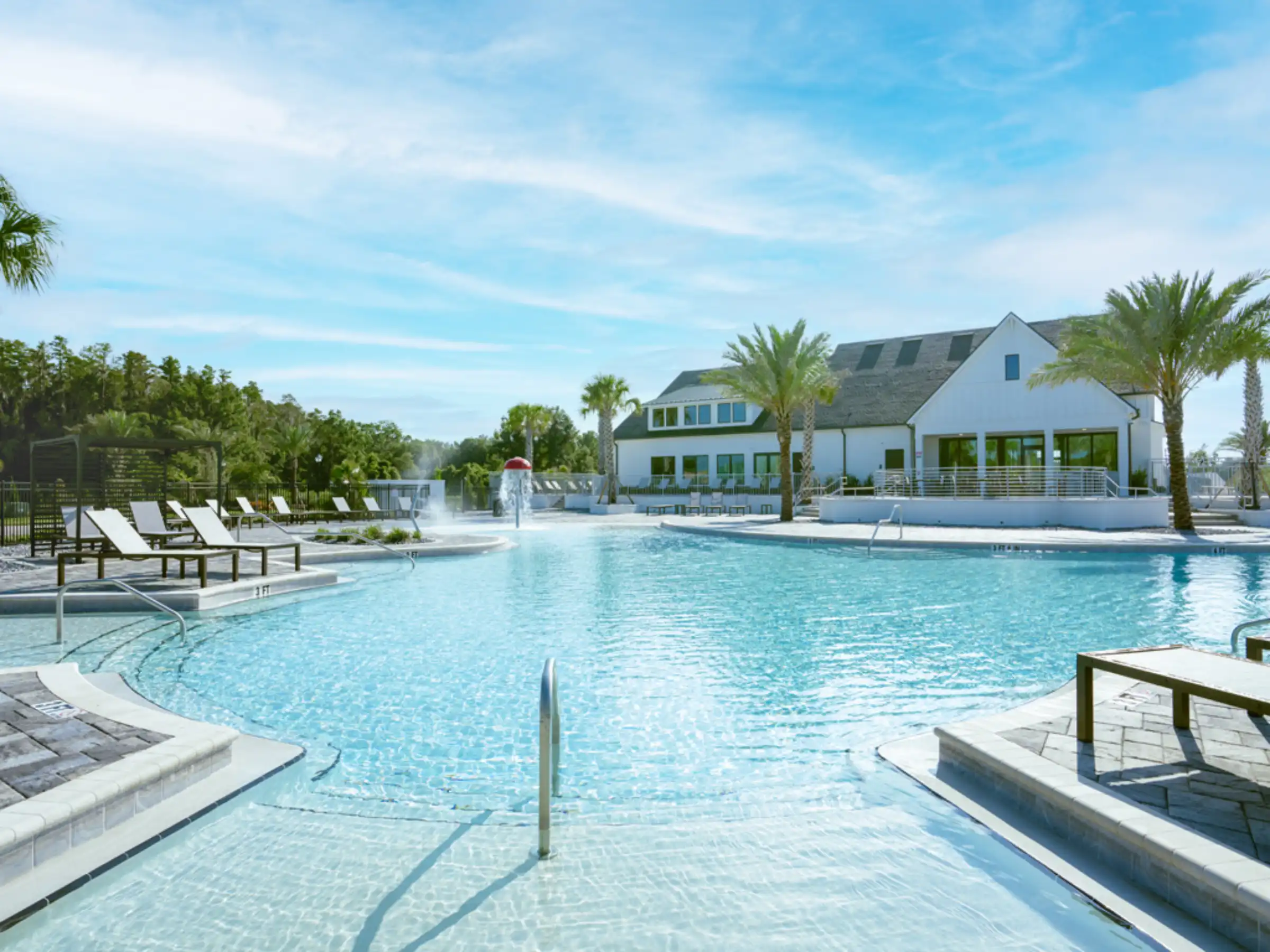 Luxury resort-style pool with modern white clubhouse, palm trees, and lounge seating overlooking St Petersburg residential community