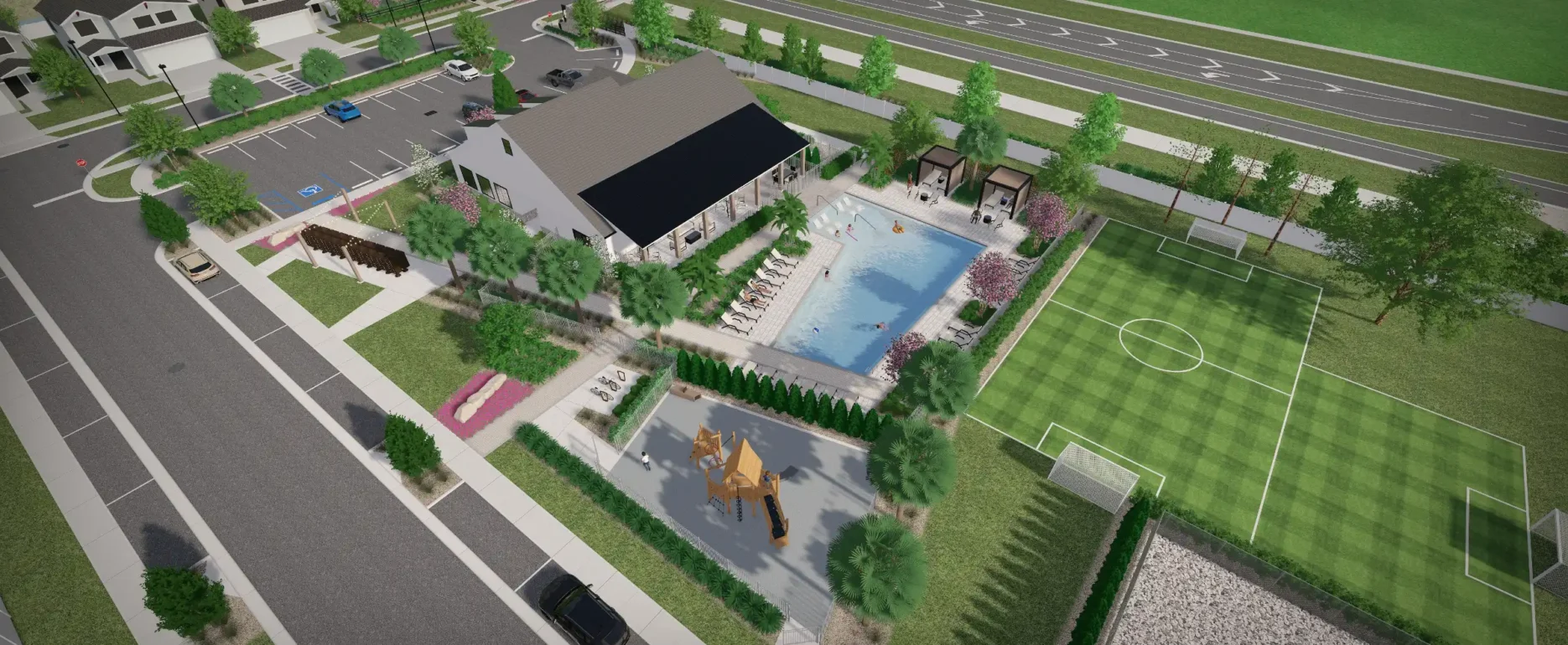 Aerial view of luxury residential community featuring Olympic-size pool, cabana structures, playground, and adjacent soccer fields with highway beyond in St Petersburg.