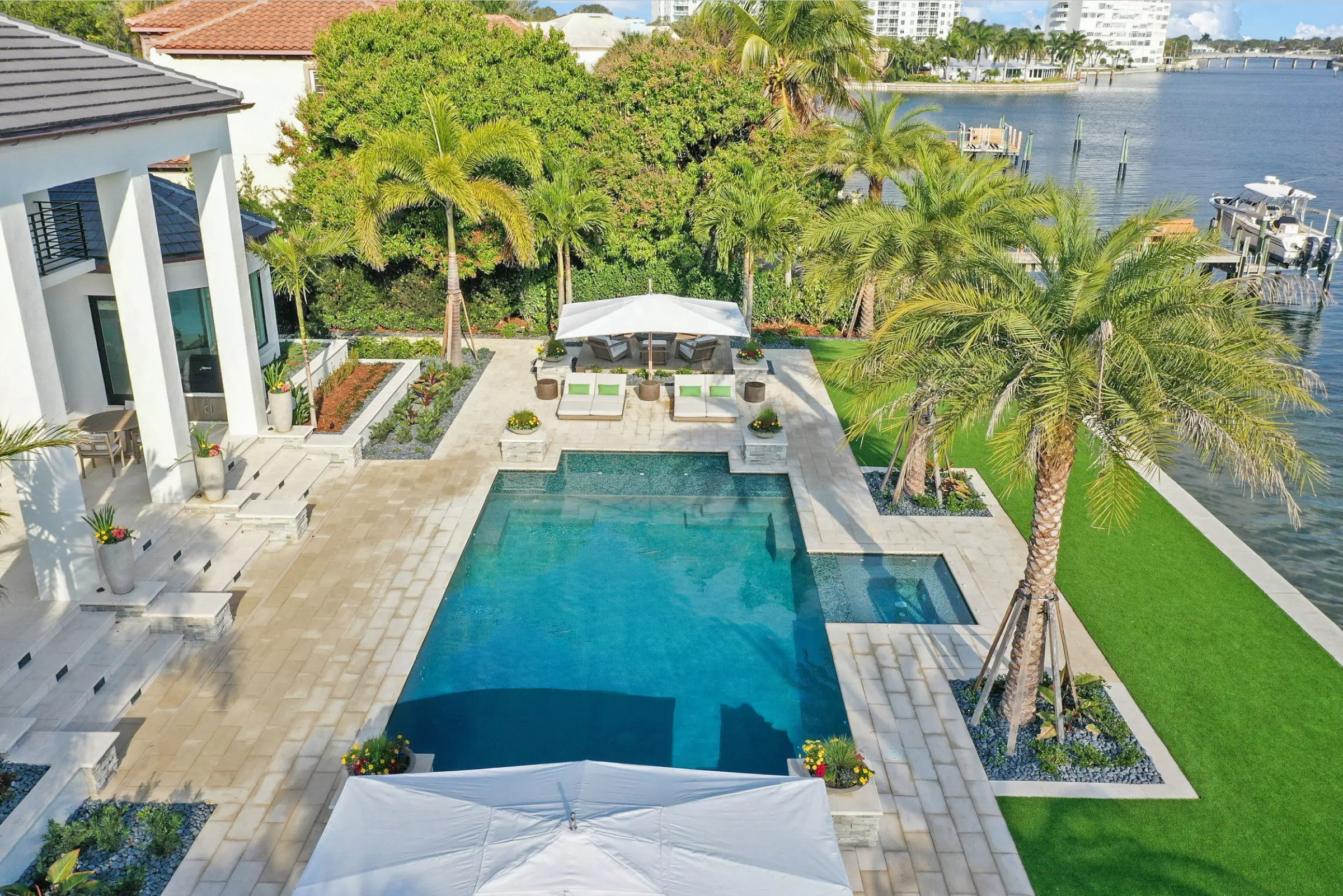 Aerial view of luxury pool design with spa, lounge seating, and manicured lawn overlooking waterfront in St Petersburg, FL residential community.