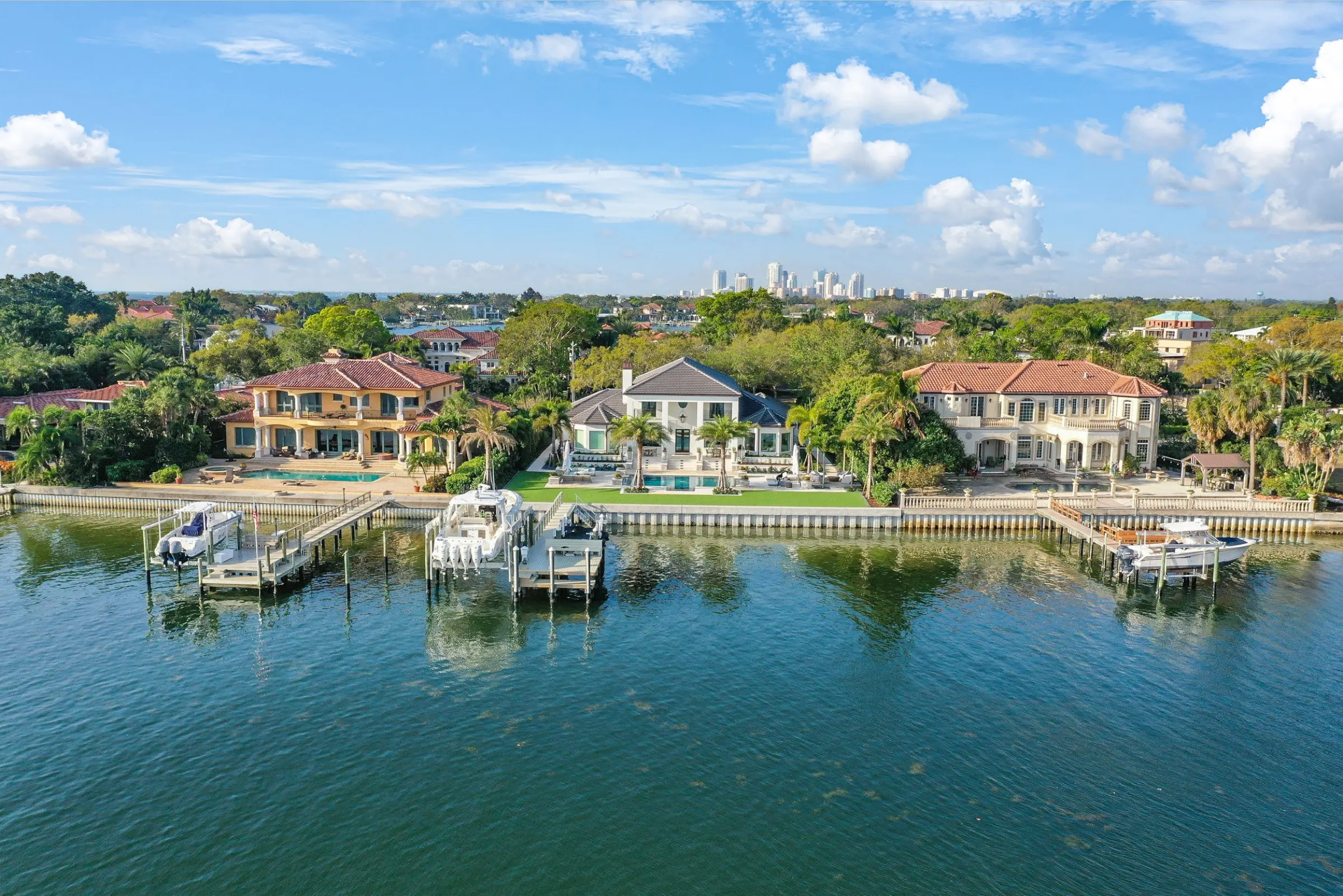Luxury waterfront homes with private docks and boats along a calm bay in St Petersburg, FL, showcasing premium residential architecture and landscape design.