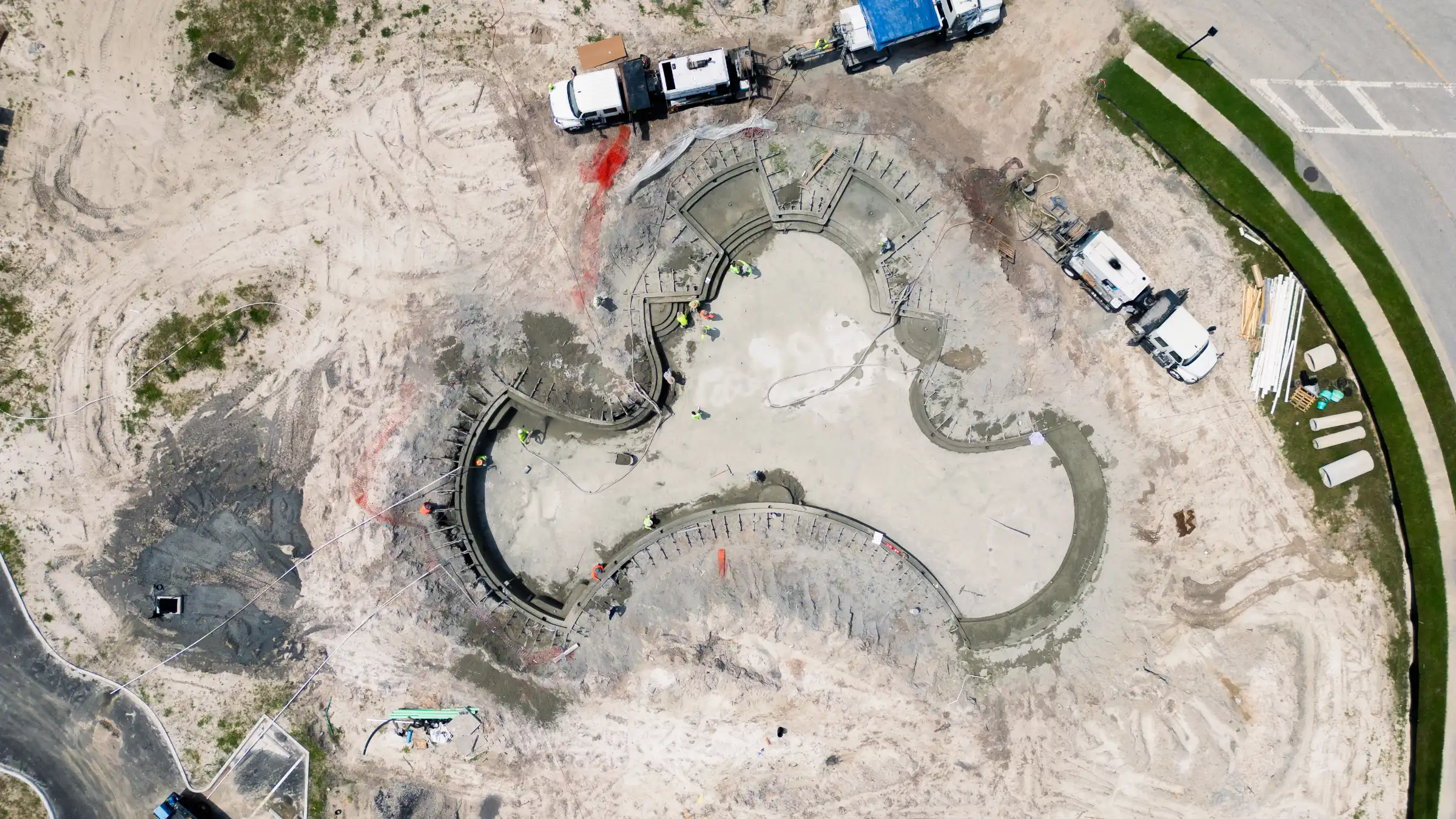 Aerial view of luxury pool design under construction in St Petersburg, featuring curved concrete deck and amphitheater-style seating with construction vehicles on-site.