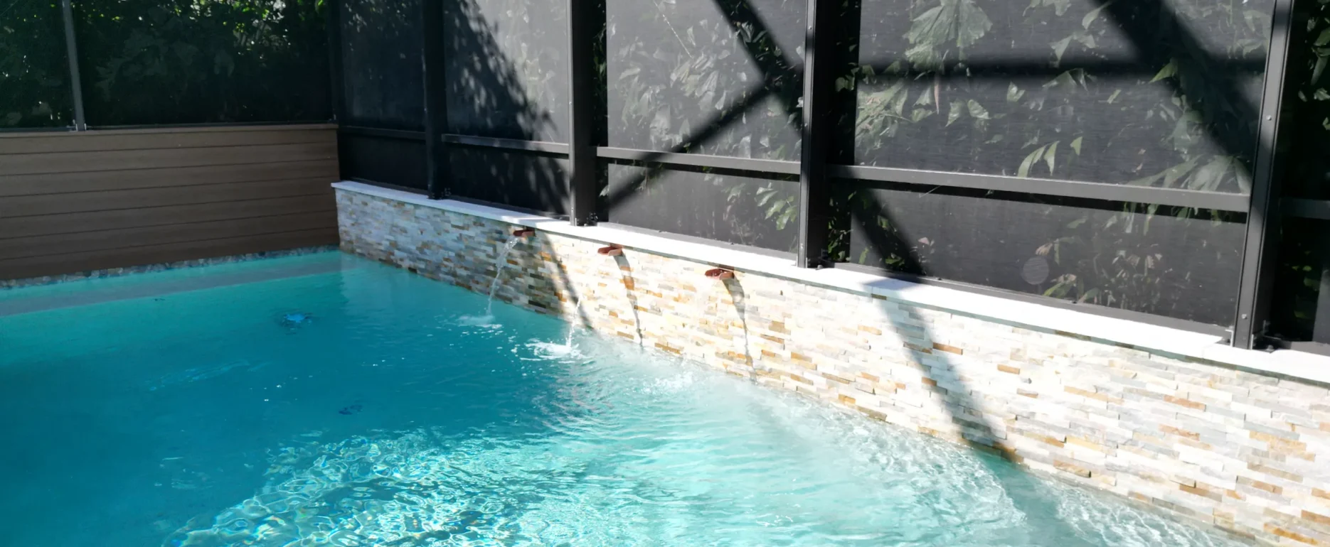 Crystal-clear turquoise swimming pool with stone waterline and black-framed screened enclosure in luxury St Petersburg residential design