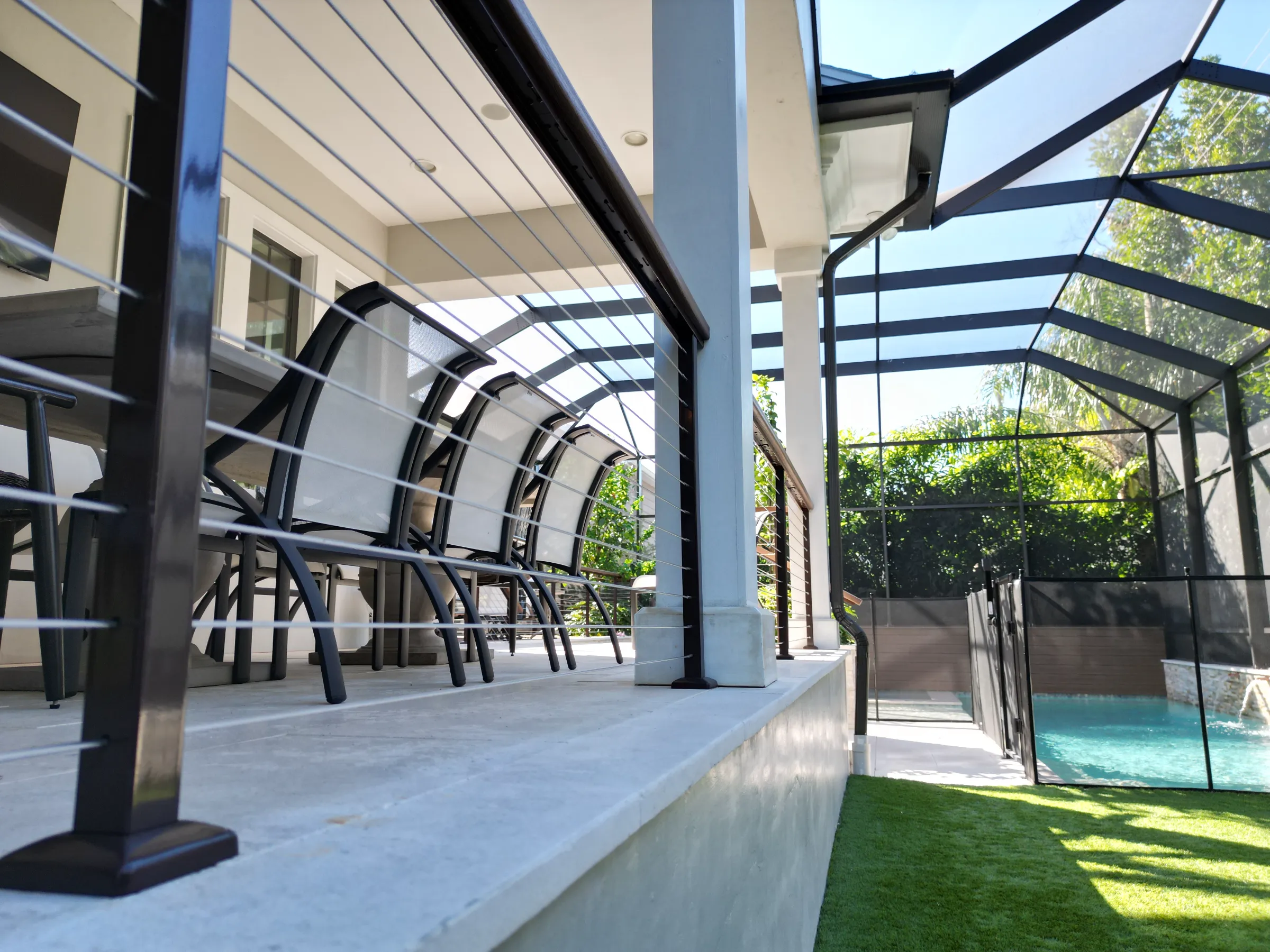 Contemporary pool deck with black pergola structure, lounge chairs, and turquoise pool visible through glass safety fencing in luxury St Petersburg residential community.