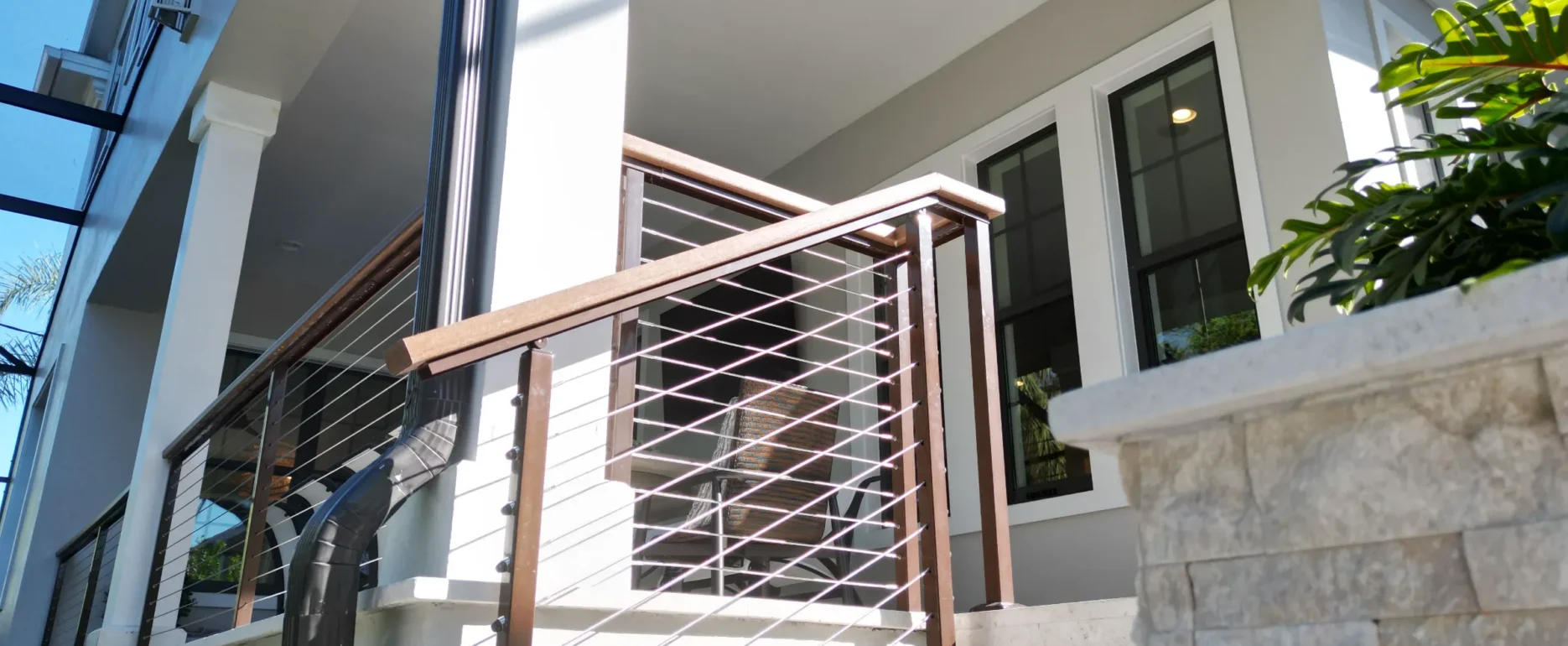 Contemporary white staircase with dark wood and metal cable railing leading to bright interior space with luxury residential architecture in St Petersburg, FL.