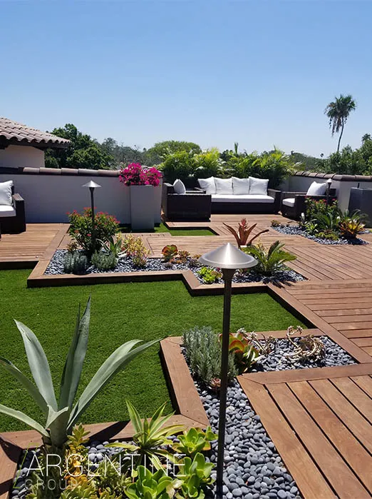 Luxury rooftop terrace in St Petersburg FL featuring composite wood decking, manicured artificial lawn, modern lounge seating, and sophisticated landscape design with ornamental plantings.