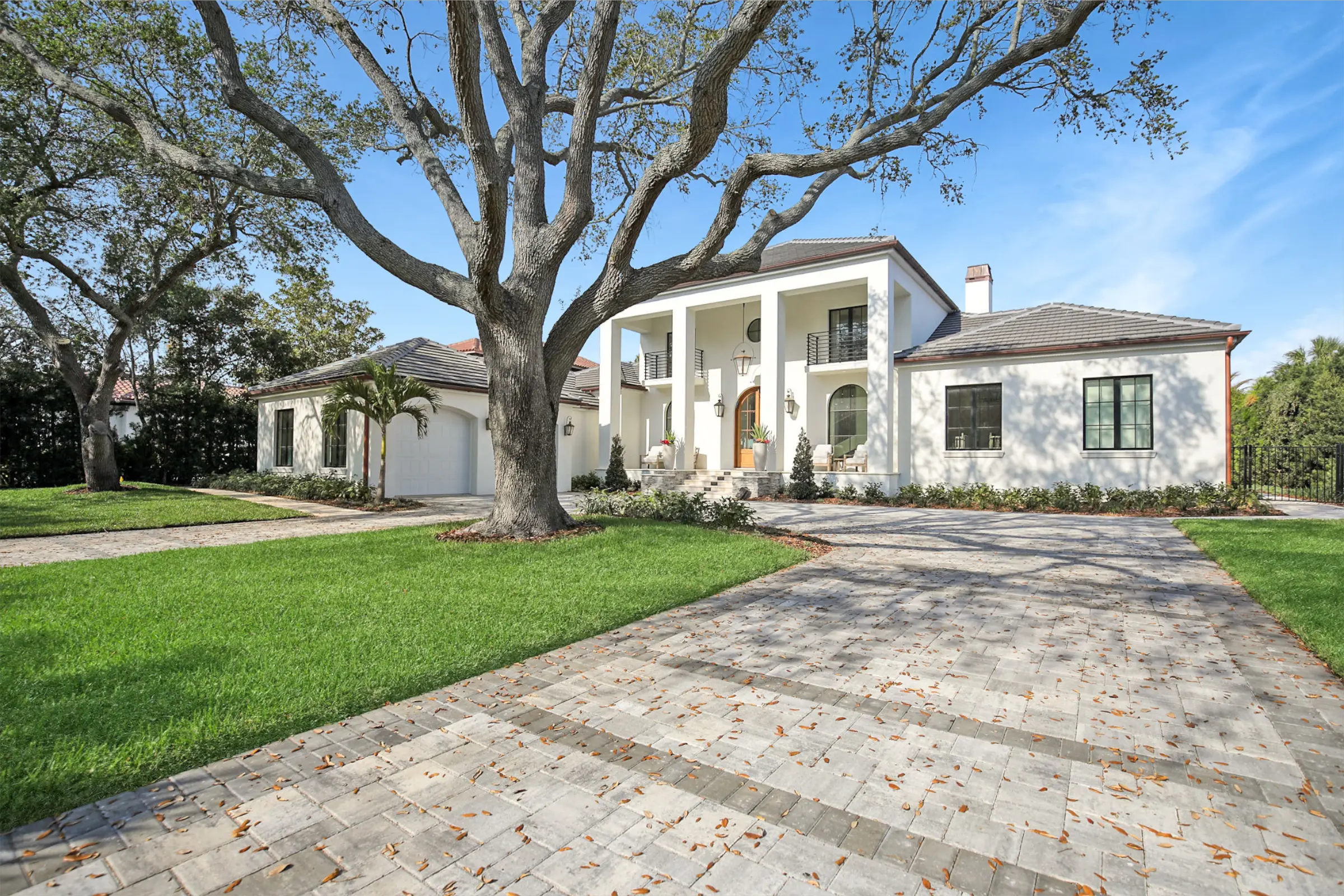 Contemporary white stucco residential home with columned portico, mature oak tree in front yard, brick paver driveway, St Petersburg FL luxury architecture