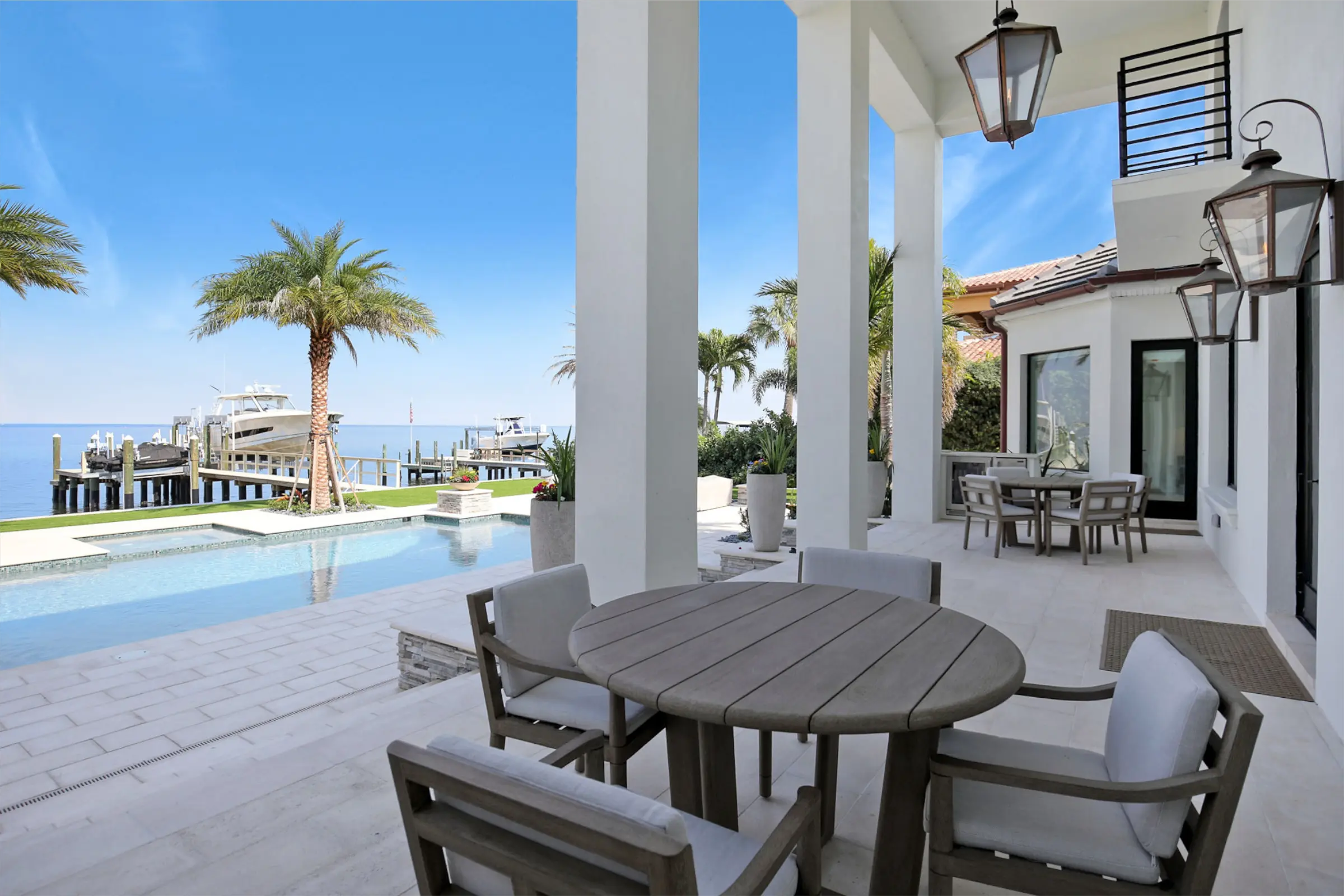 Luxury waterfront patio featuring dining table, pool, and bay view with boats docked at private marina in St Petersburg, Florida.