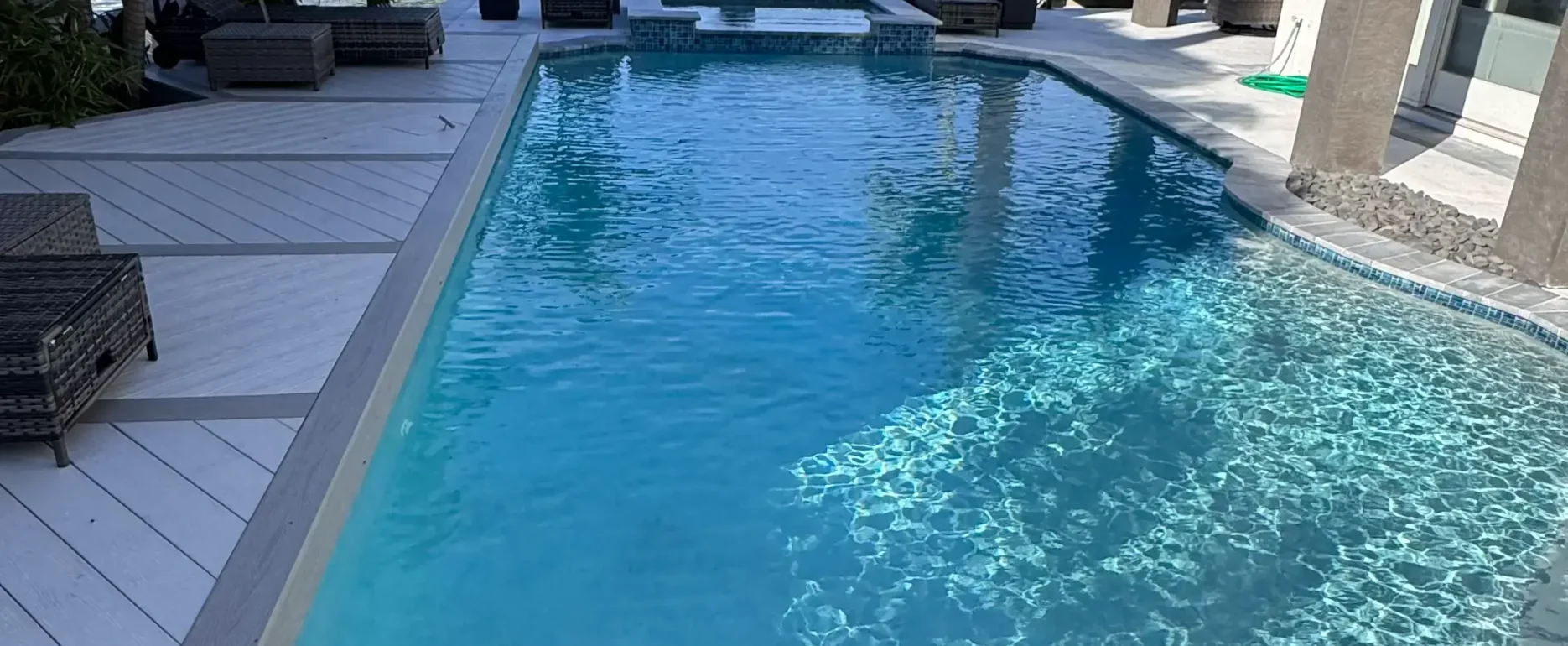 Luxury pool overlooking waterfront with modern home, palm trees, and boat docks in St Petersburg residential community