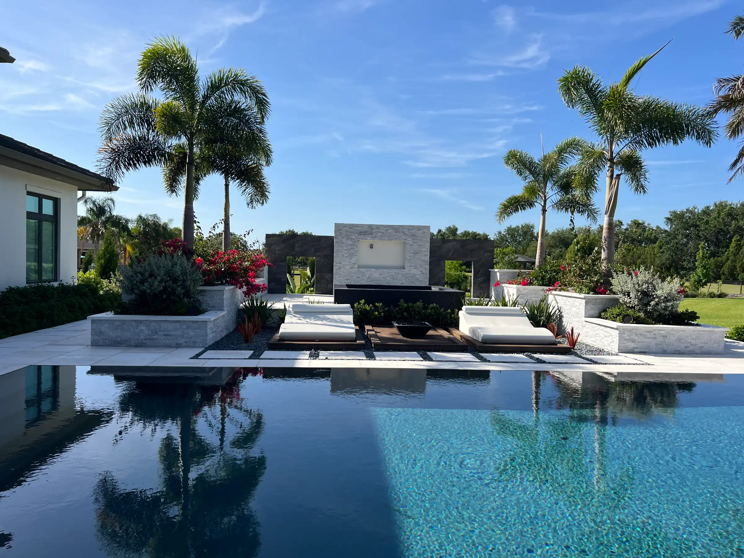 Luxury residential pool with stone deck, modern architectural features, and tall palm trees in St Petersburg, FL landscape design