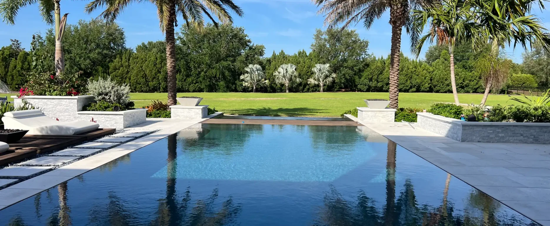 Luxury infinity pool with palm trees and manicured lawn, exemplifying premium pool design and landscape architecture in St Petersburg FL residential communities.