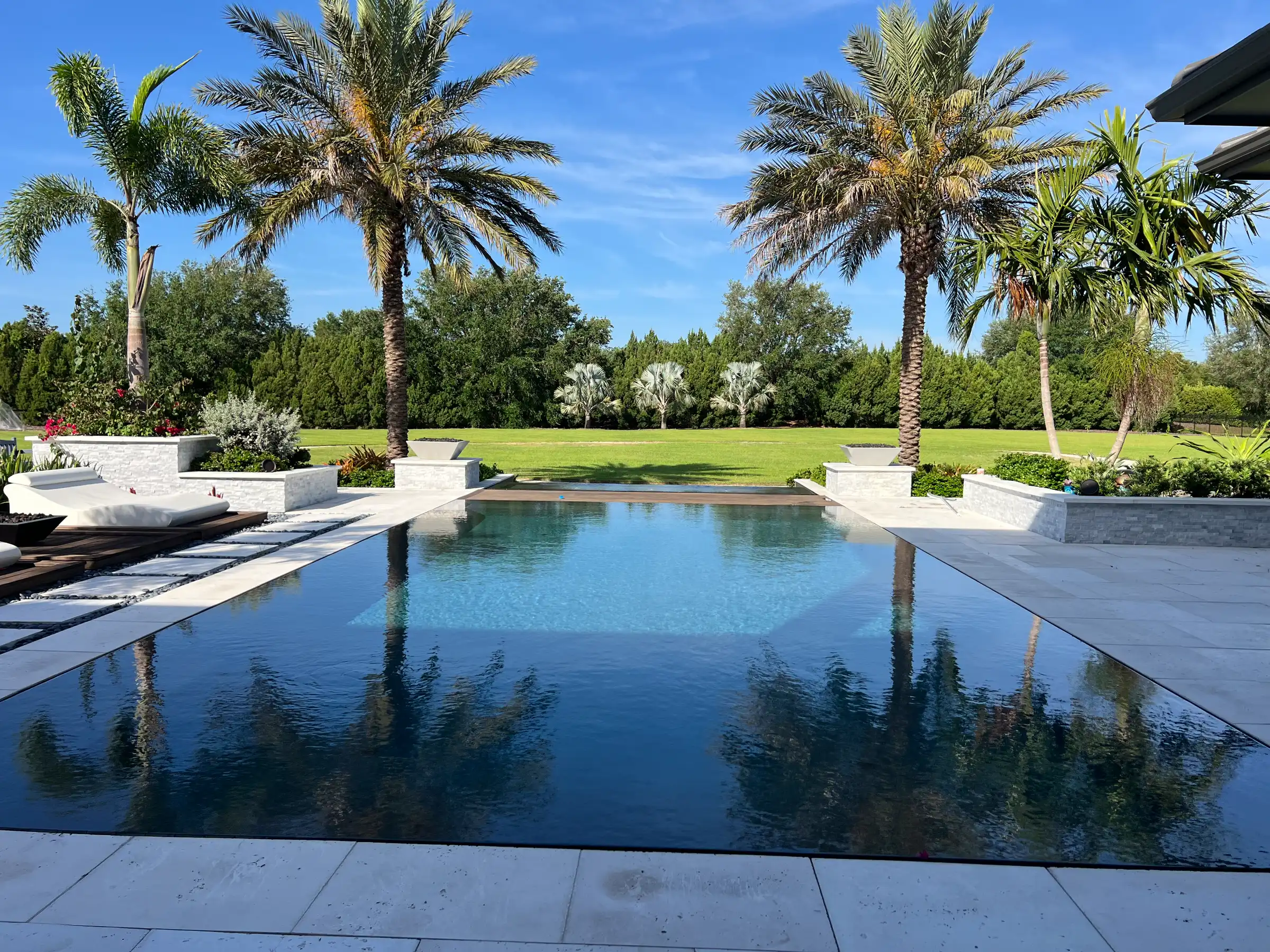 Luxury infinity pool with palm trees and manicured lawn, exemplifying premium pool design and landscape architecture in St Petersburg FL residential communities.