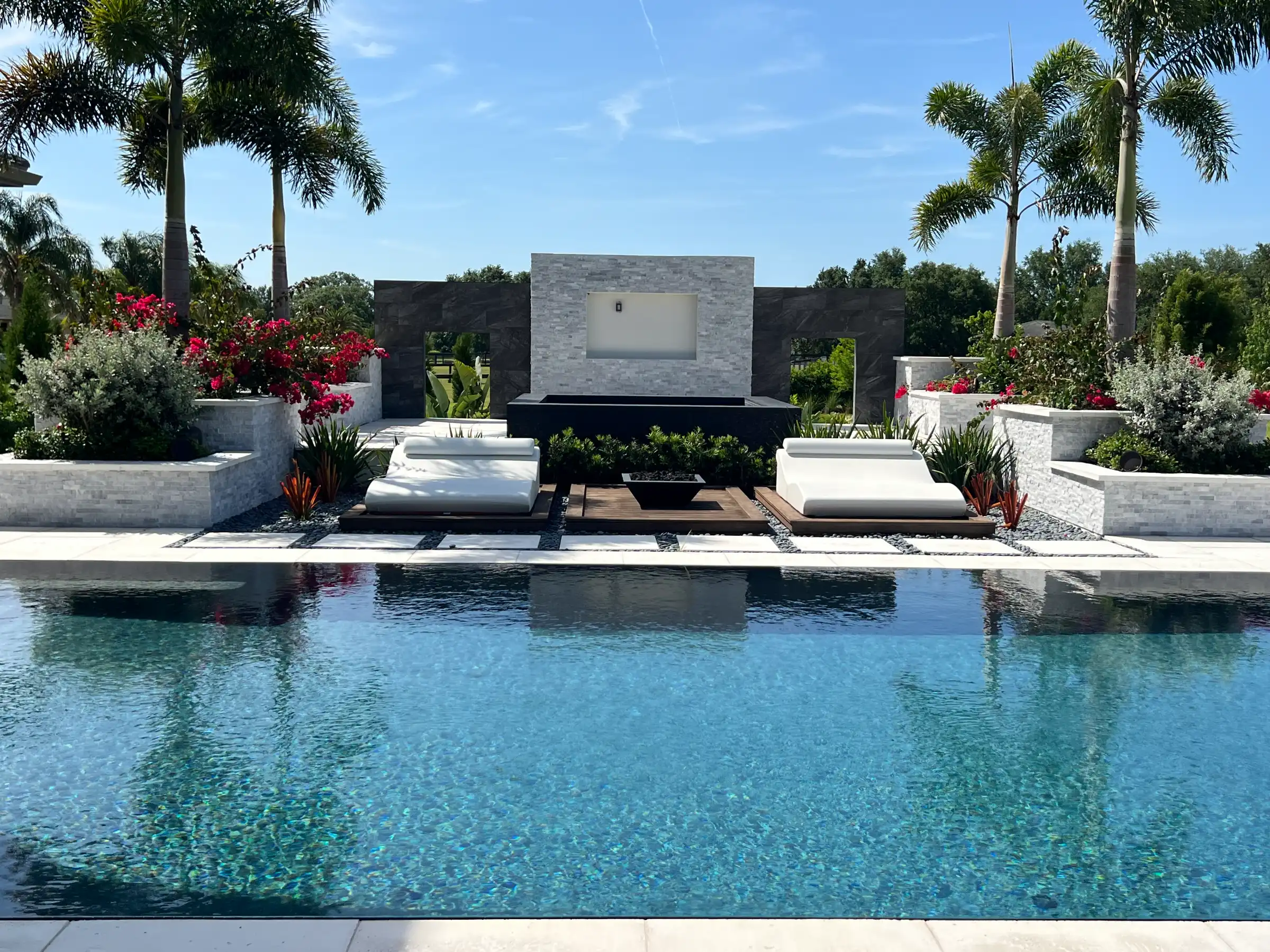 Luxury pool deck with modern pavilion, white lounge seating, and lush tropical landscaping in St Petersburg residential community.