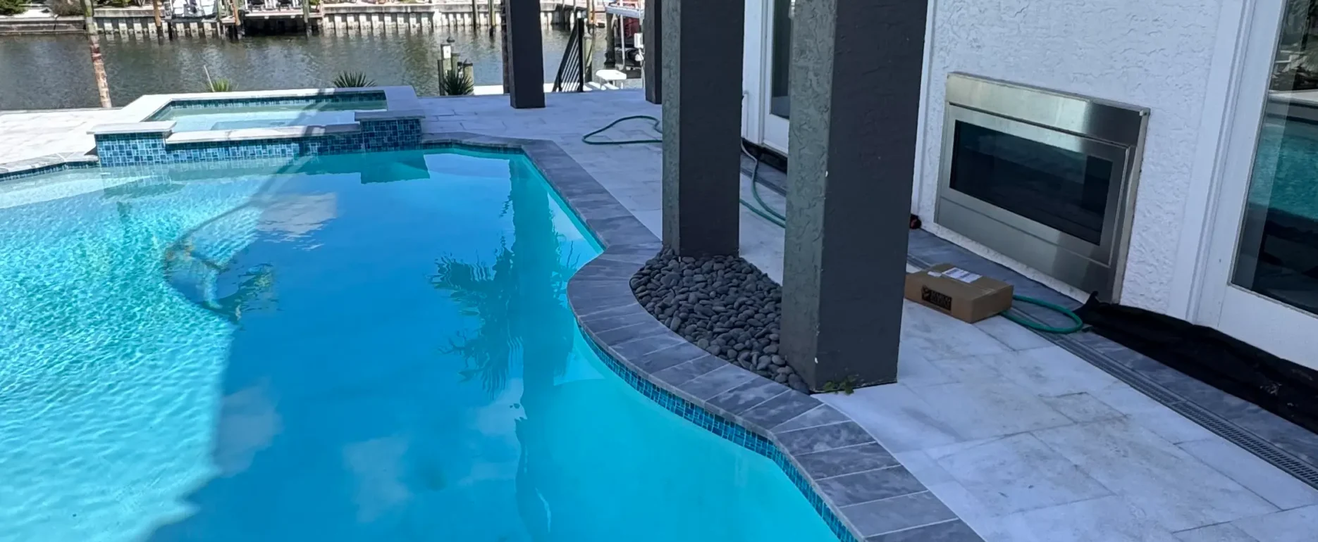 Curved luxury pool with spa overlooking St Petersburg waterfront canal, featuring contemporary architectural design and premium landscape construction.
